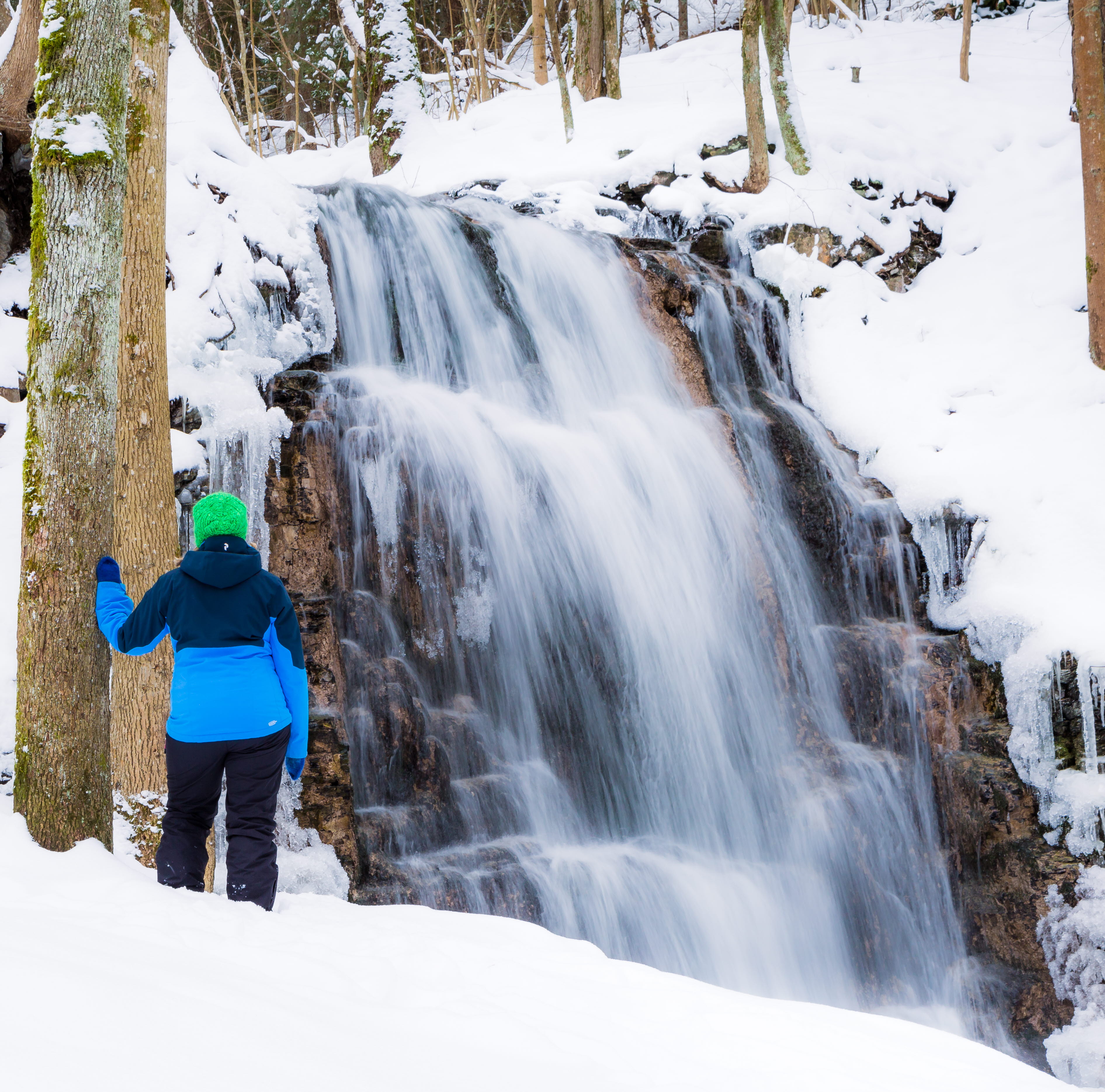 En person står framför Silverfallet, det är vintertid och fallet har frusit. 