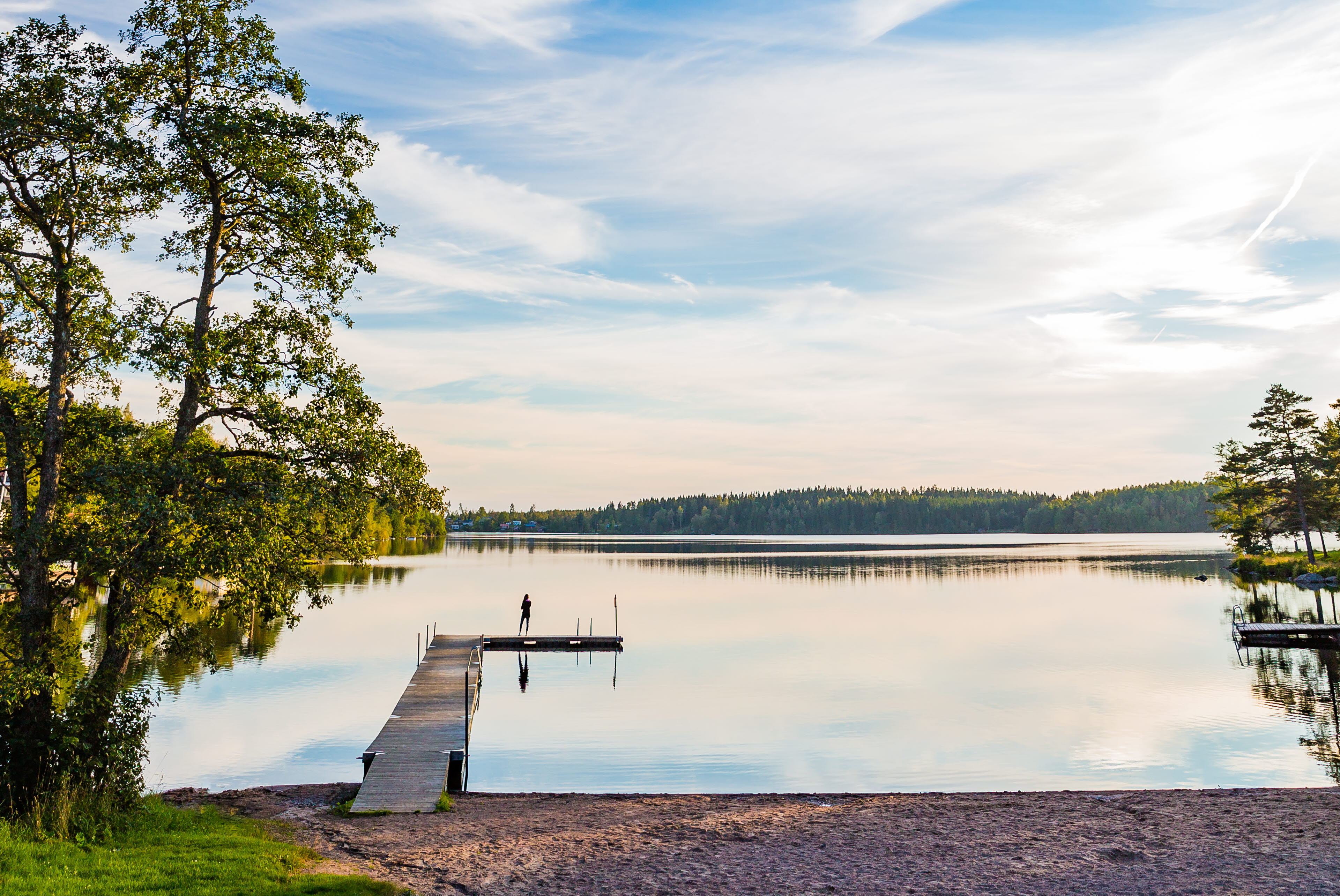 Utsikt över en brygga och en sjö med lätta moln och blå himmel. 