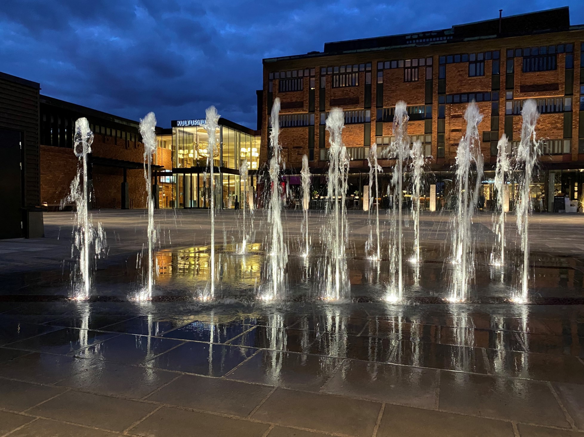Kvällsbelysning vid en fontän som pryder en av ingångarna till Skövde kulturhus. 