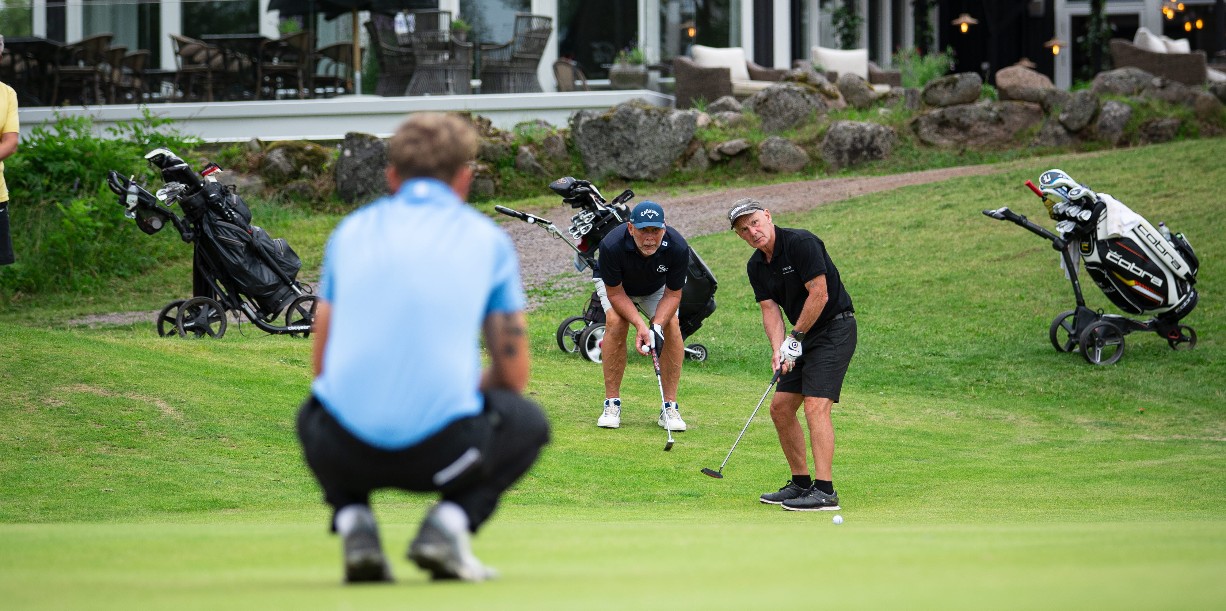 Golfspelare som spelar golf framför en restaurangbyggnad