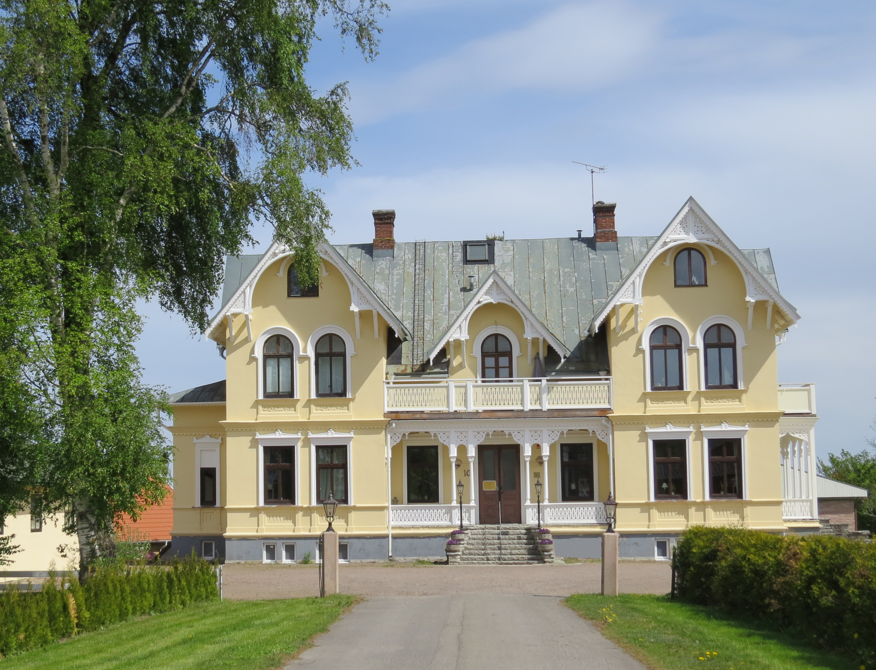 Skövde Vandrarhem som ligger i en gul sekelskiftesvilla med vit snickarglädje.