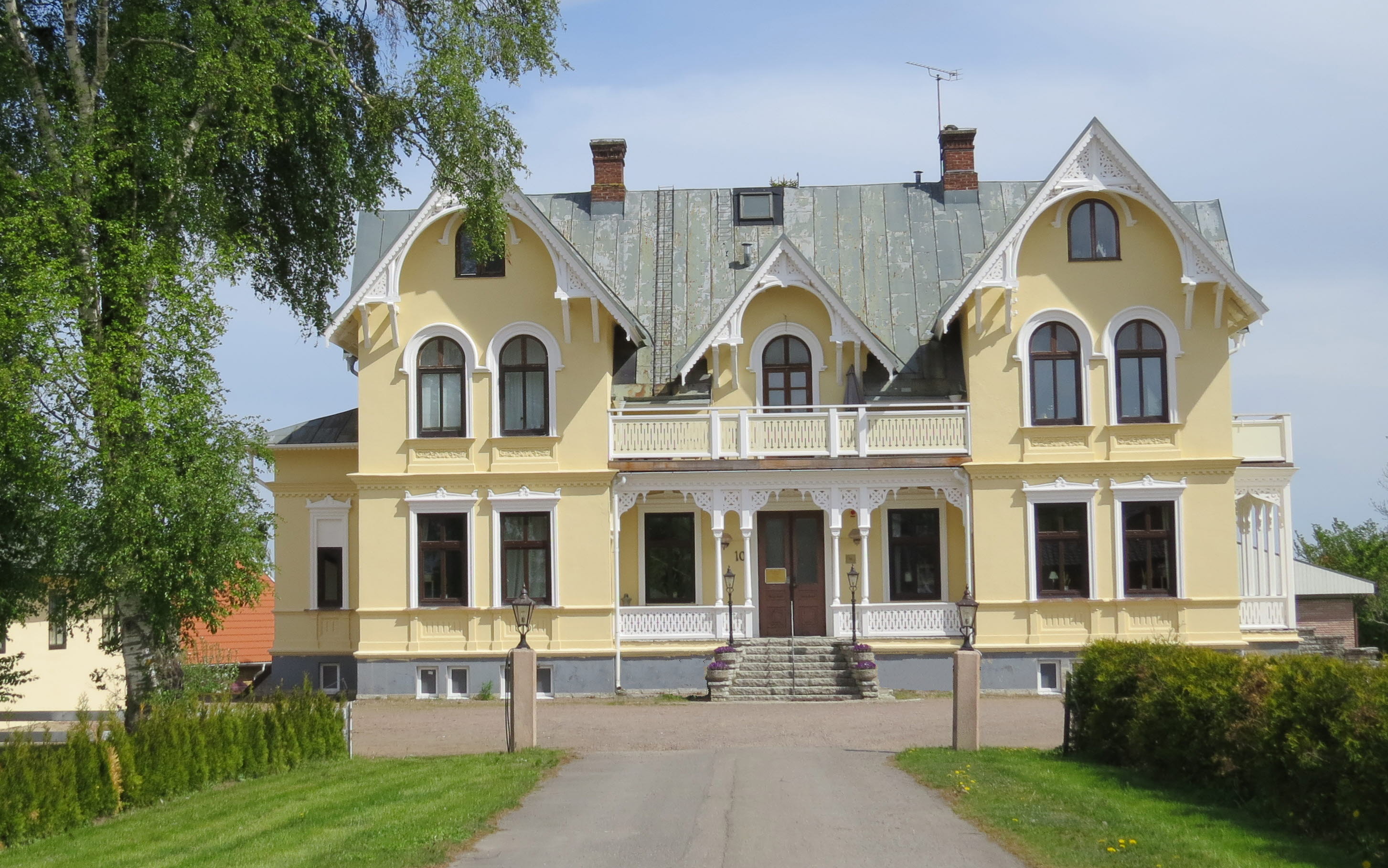 Skövde Vandrarhem som ligger i en gul sekelskiftesvilla med vit snickarglädje.
