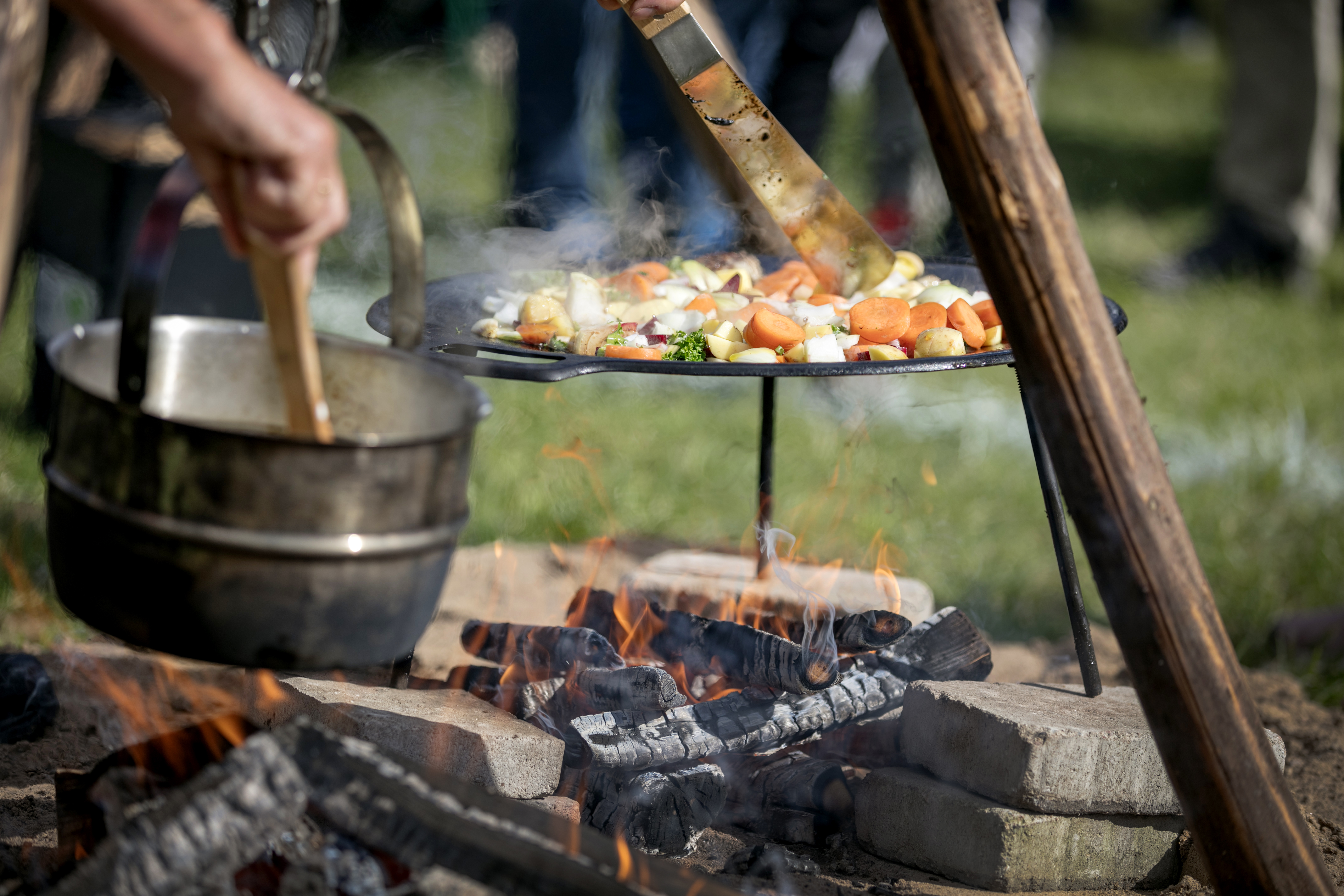 Utomhusmatlagning, grönsaker och rotfrukter tillagas på muurikaa över öppen eld.