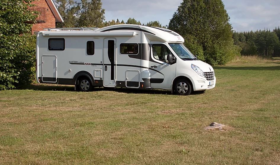 En vit husbil står på en gräsmatta. 