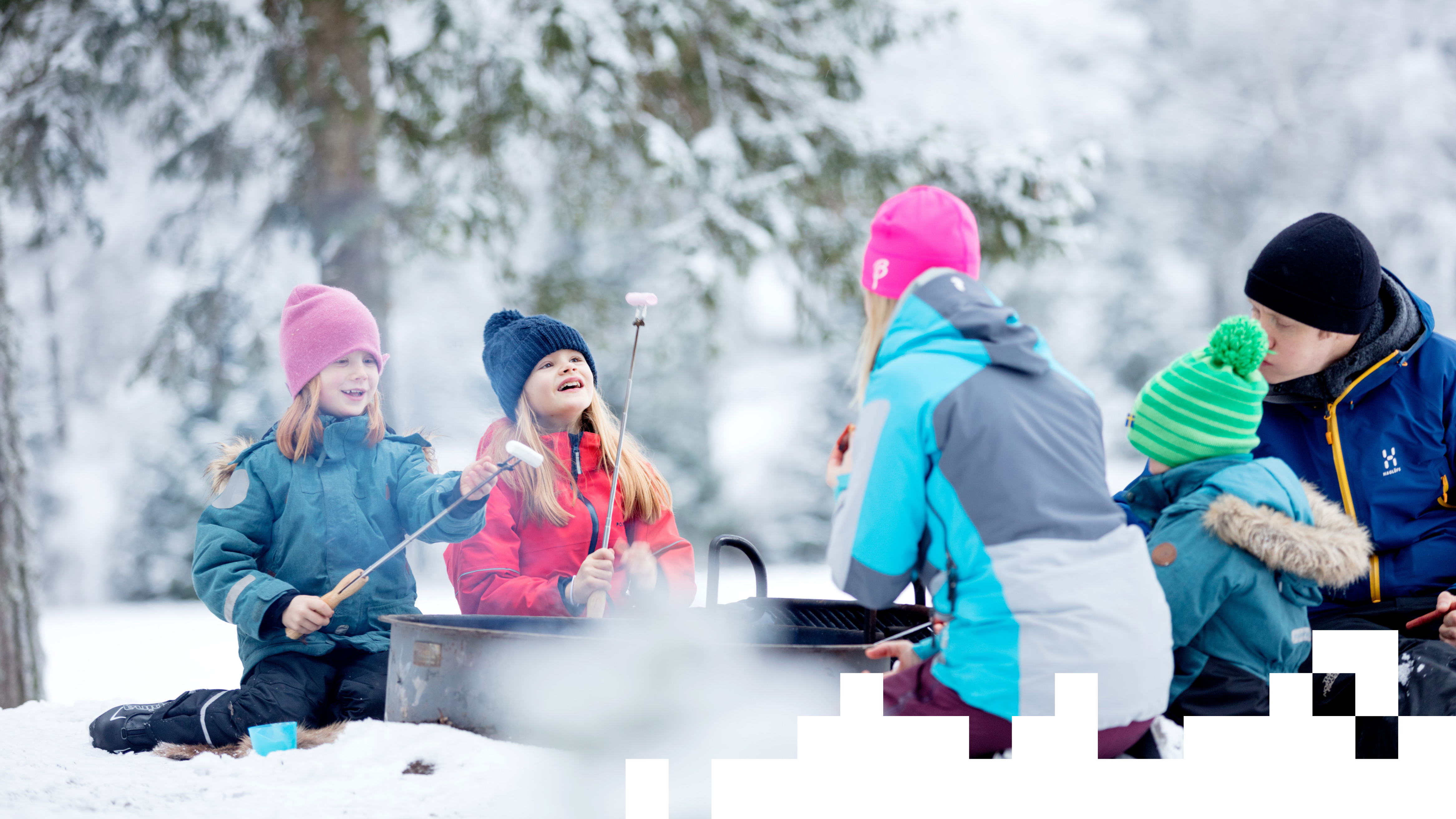 A family sitting outside in the snow eating hot dogs. 