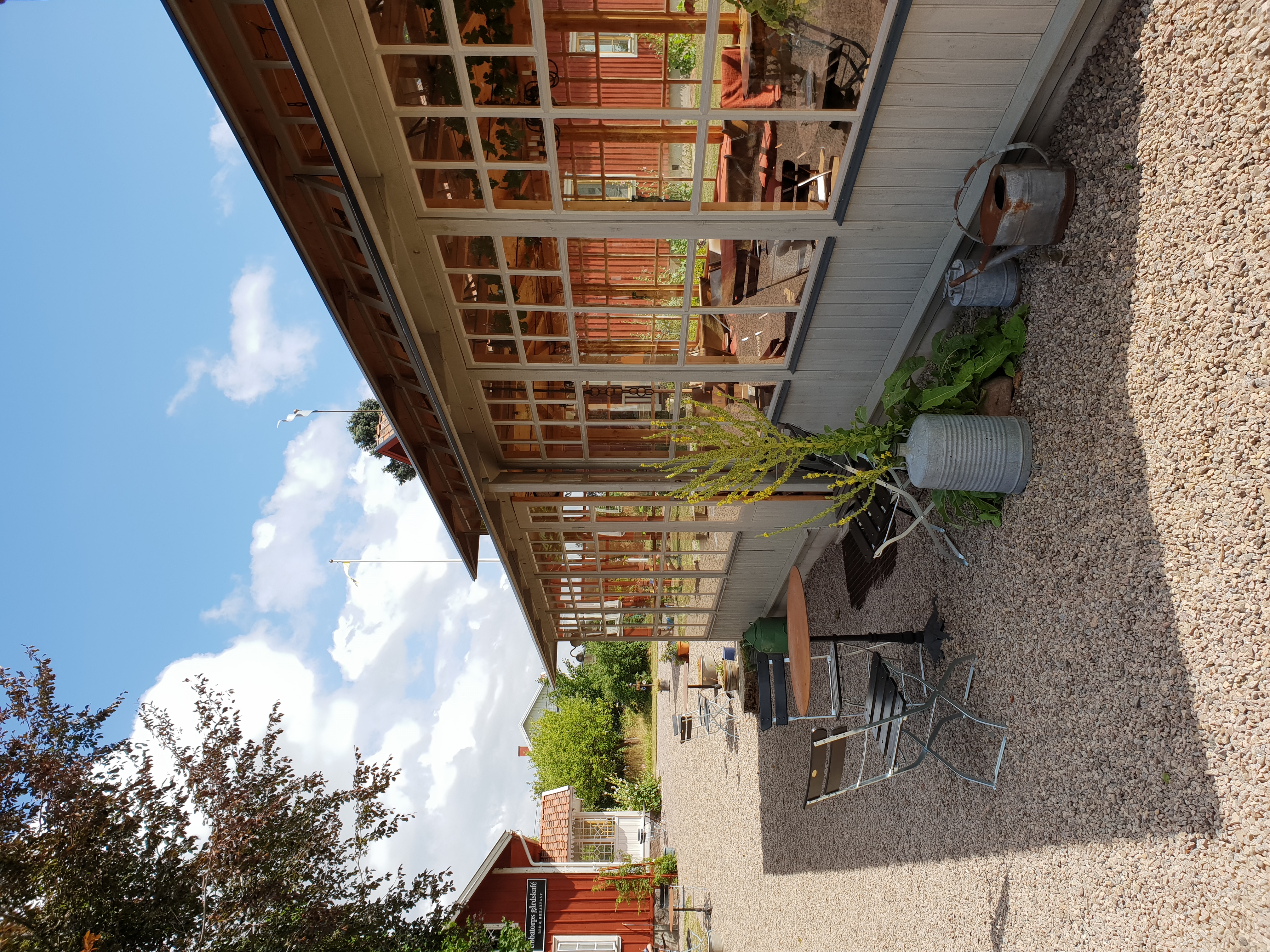 A blue sky over a building with large beautiful windows. Inside you can see a cozy café. 