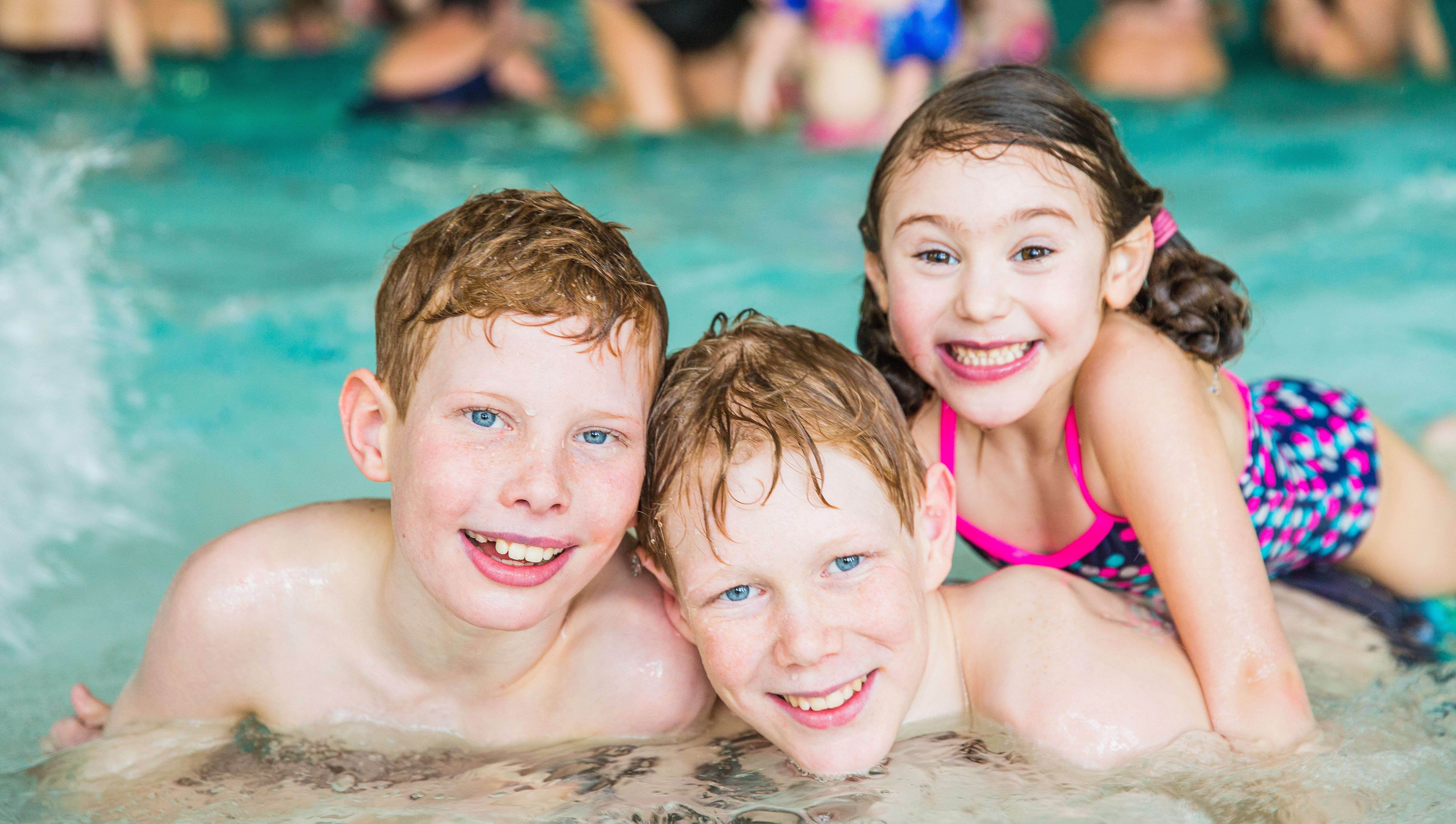 Three children are posing in front of the camera in the water at Arena Skövde
