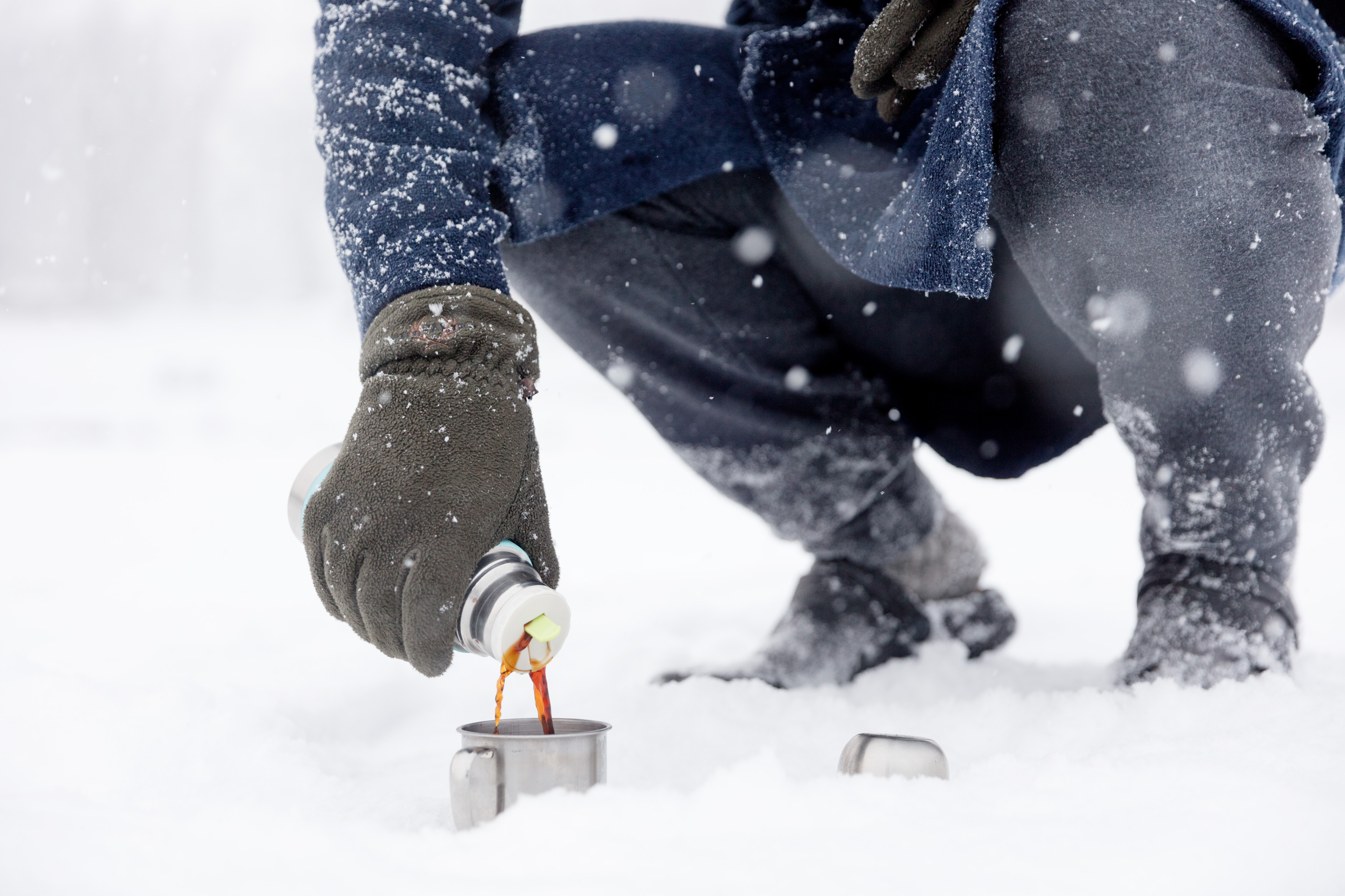 En vinterbadare häller upp varm dryck i snölandskap vid Simsjön i Skövde. 