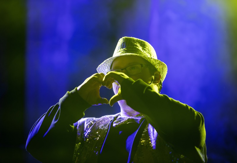 En kille som håller handen som ett hjärta och har på sig en hatt.