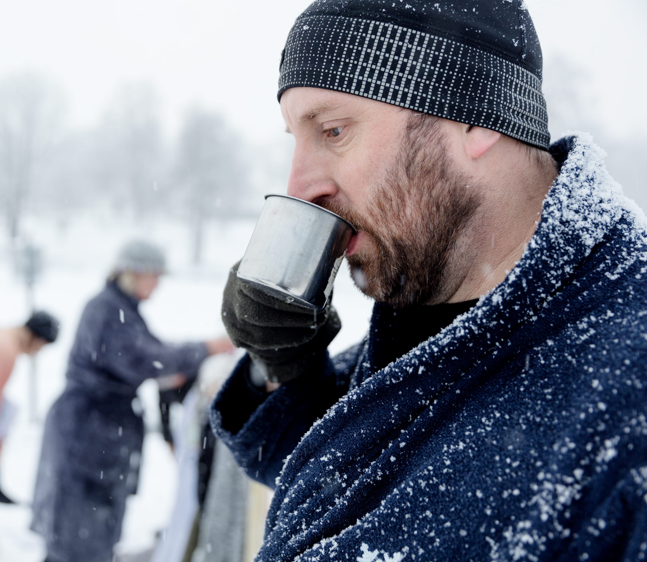 Vinterbadare dricker varm dryck i snölandskap vid Simsjön i Skövde. 