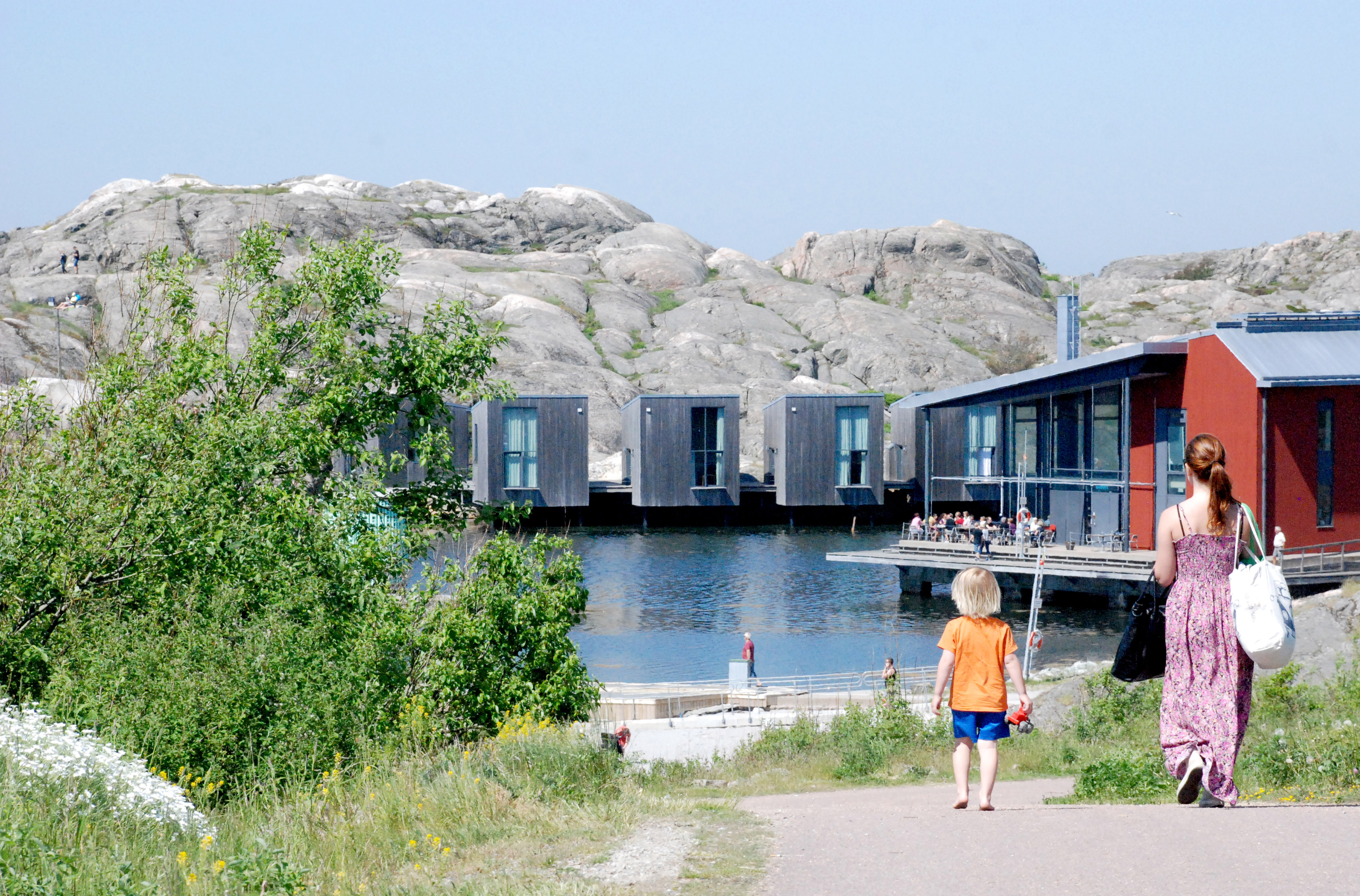 Barn och vuxen promenerar i solen mot Nordiska Akvarellmuseet