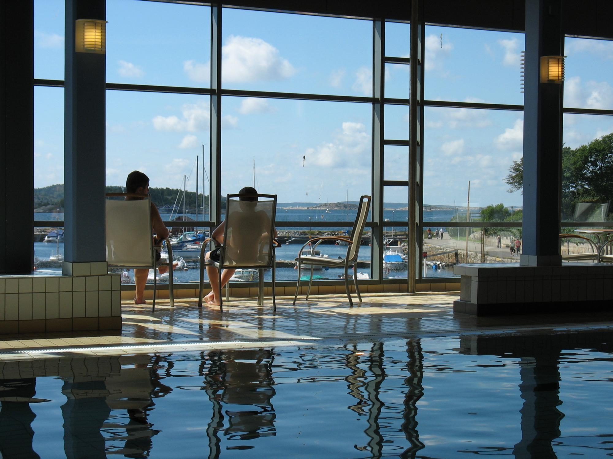 Two people are sitting inside the bathhouse, looking at the southern harbour through the window. 