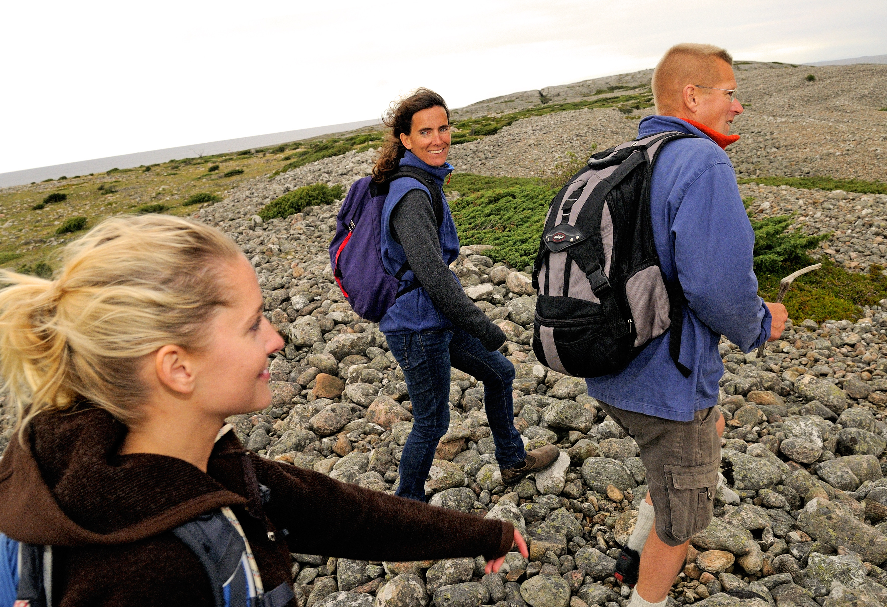 Tre personer vandrar över ett klapperstensfält på Kosteröarna. 