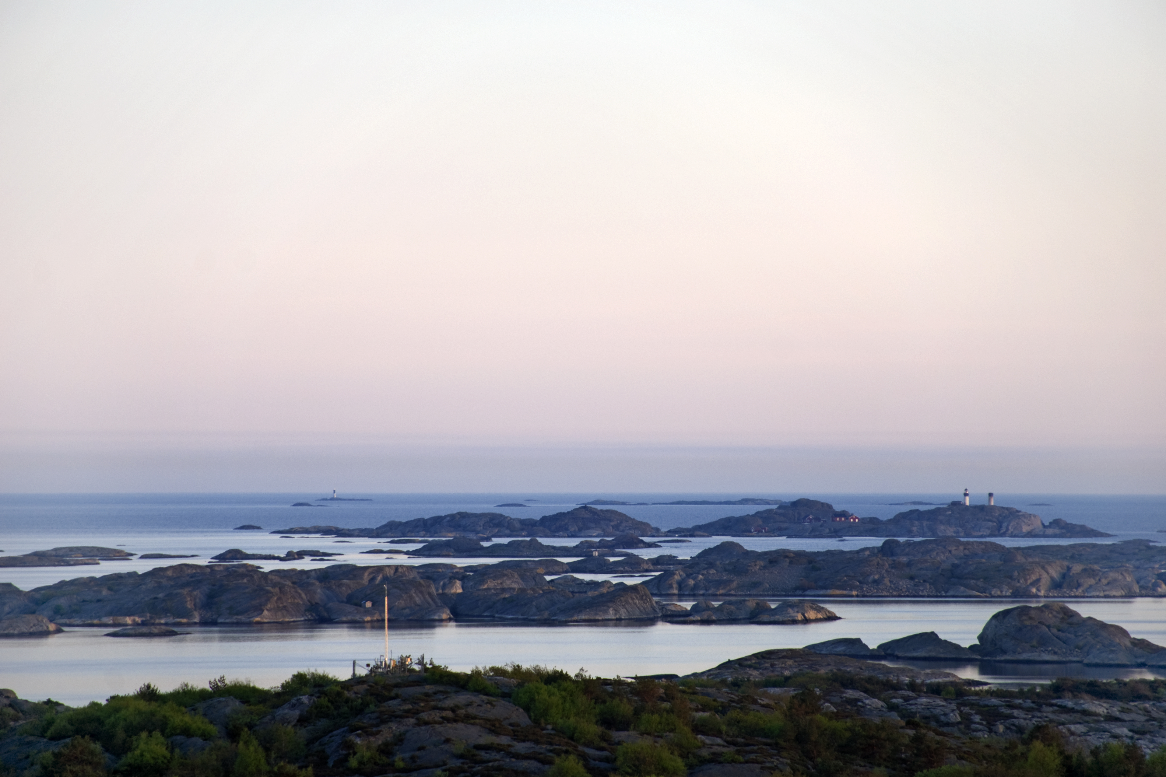 Rosa skymningsljus över Kosterarkipelagen med Ursholmen fyrplats i bakgrunden. Bilden är tagen från Valfjäll, Sydkoster.