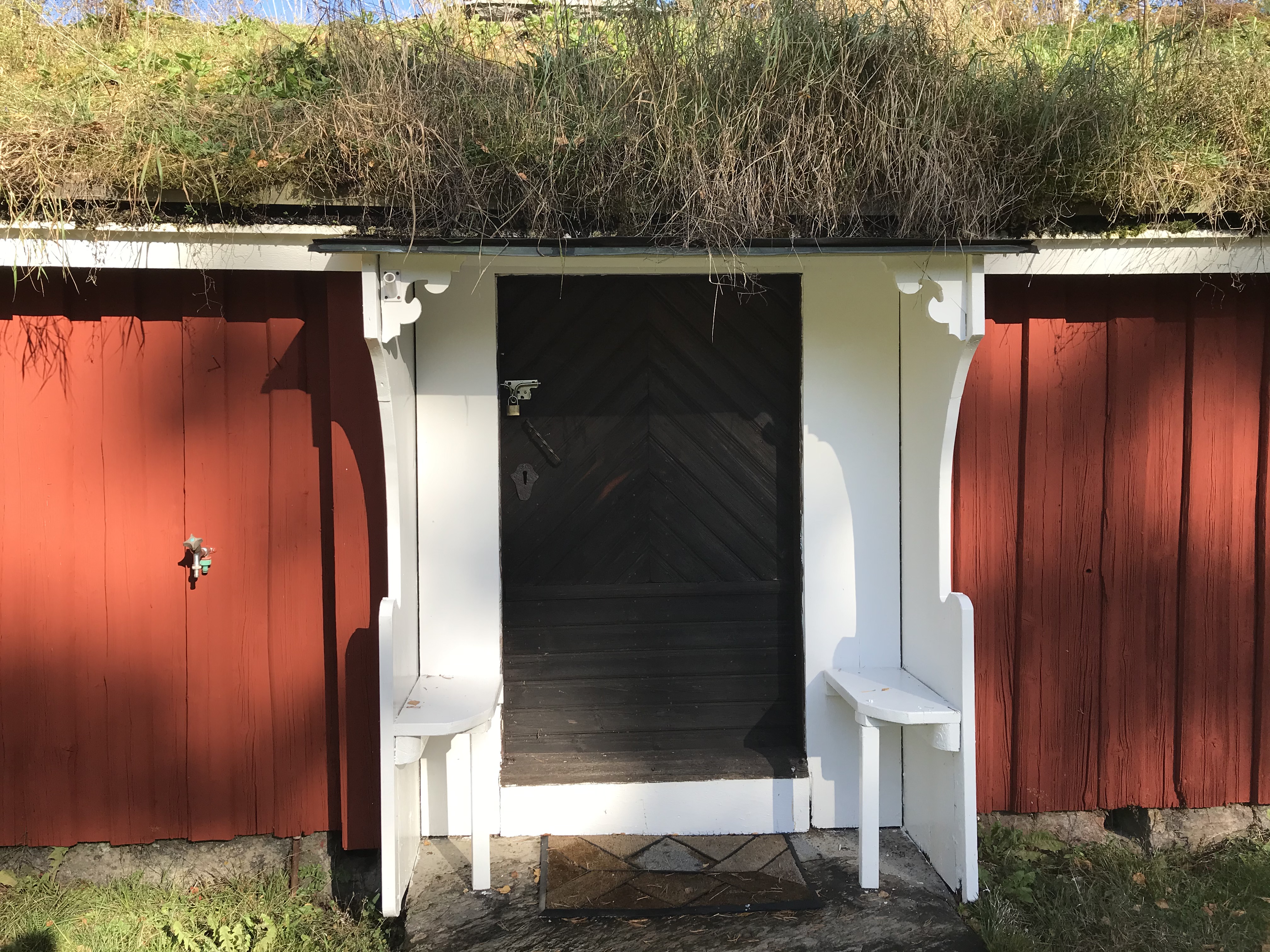 Röd gammal byggnad med grästak, Olofsbygget i Håcksvik