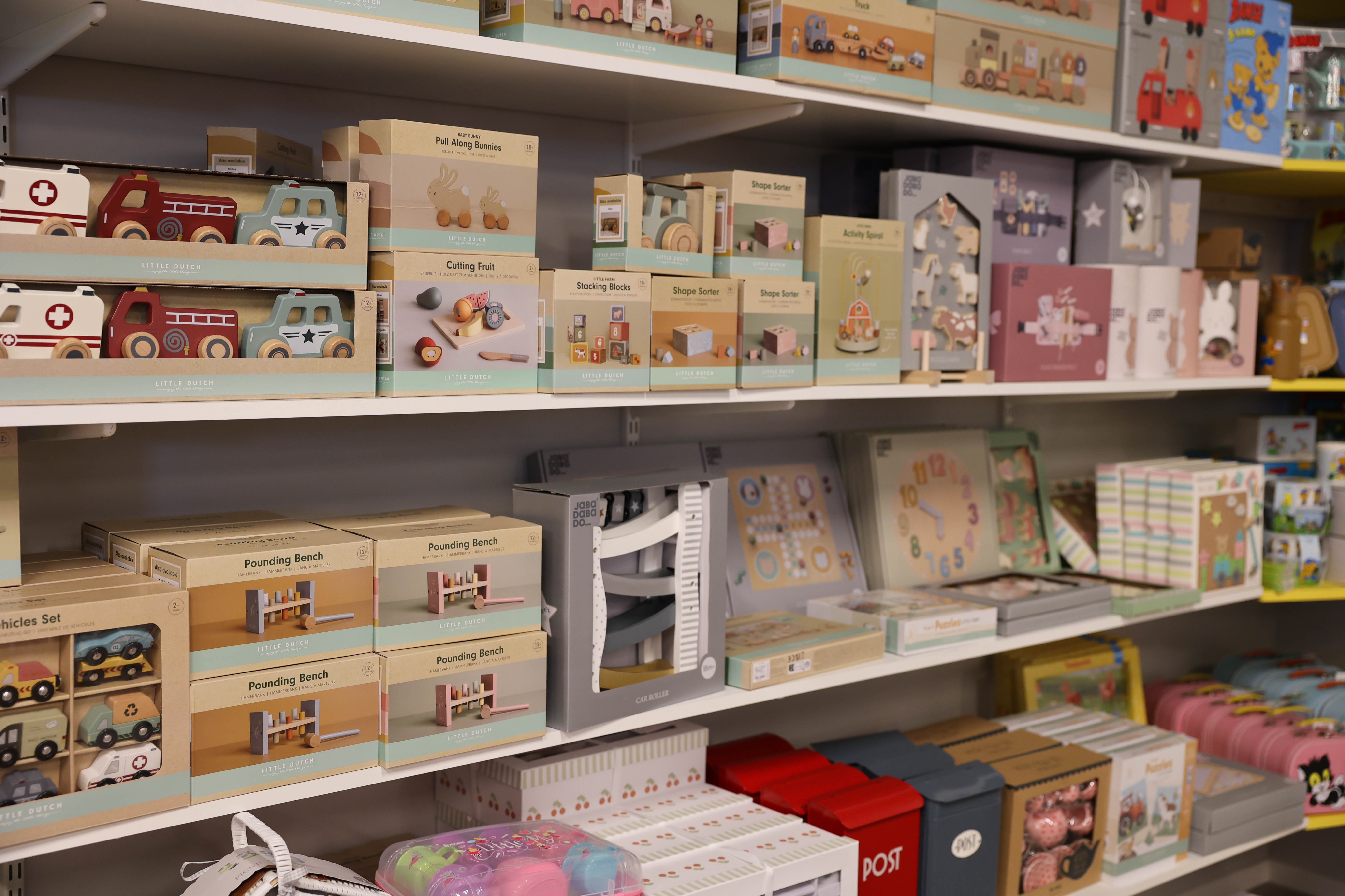 Butikshylla med leksaker och barnprodukter i olika färger och teman.