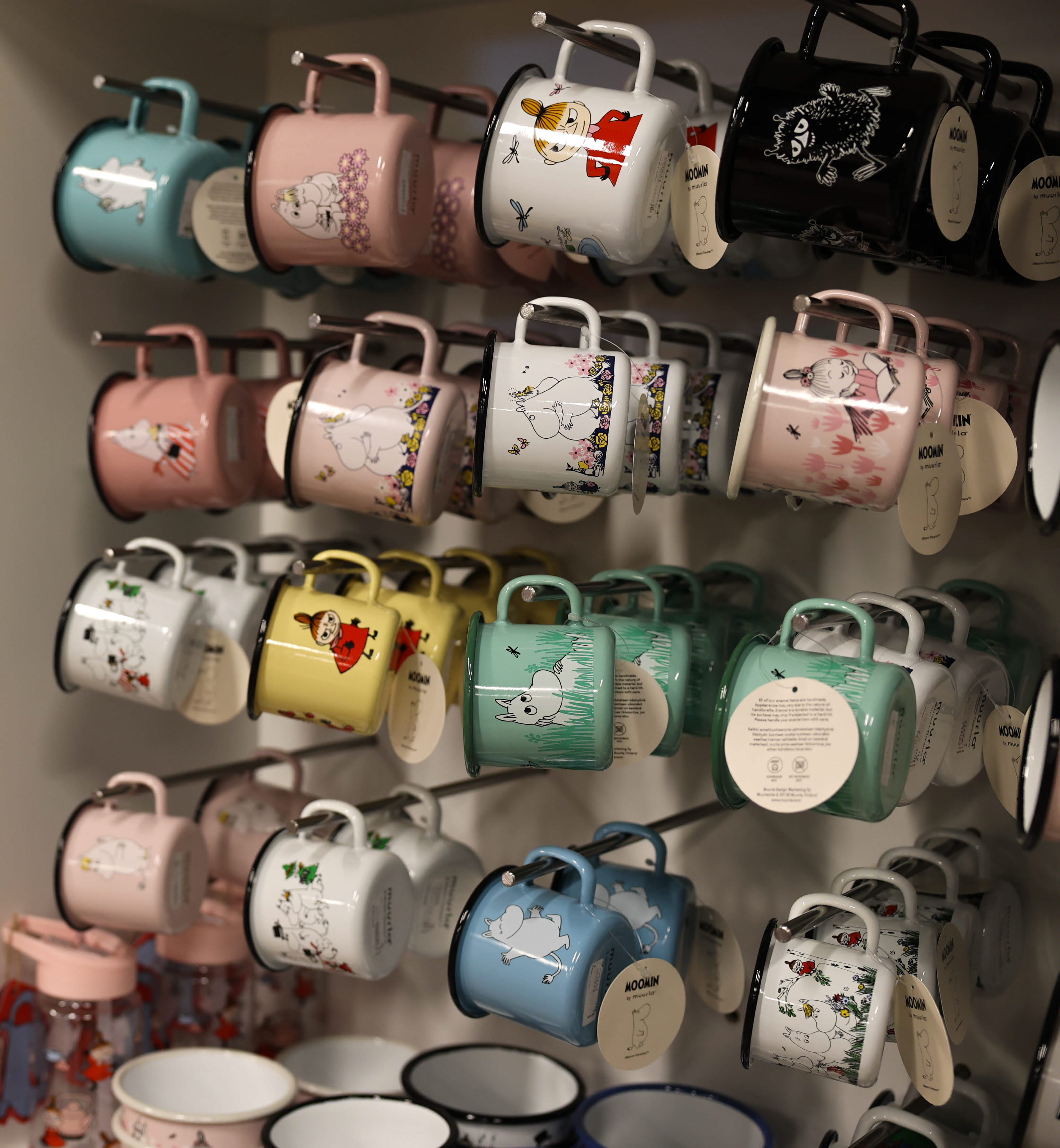 Butikshylla med färgglada Mumin-muggar i olika motiv och färger.