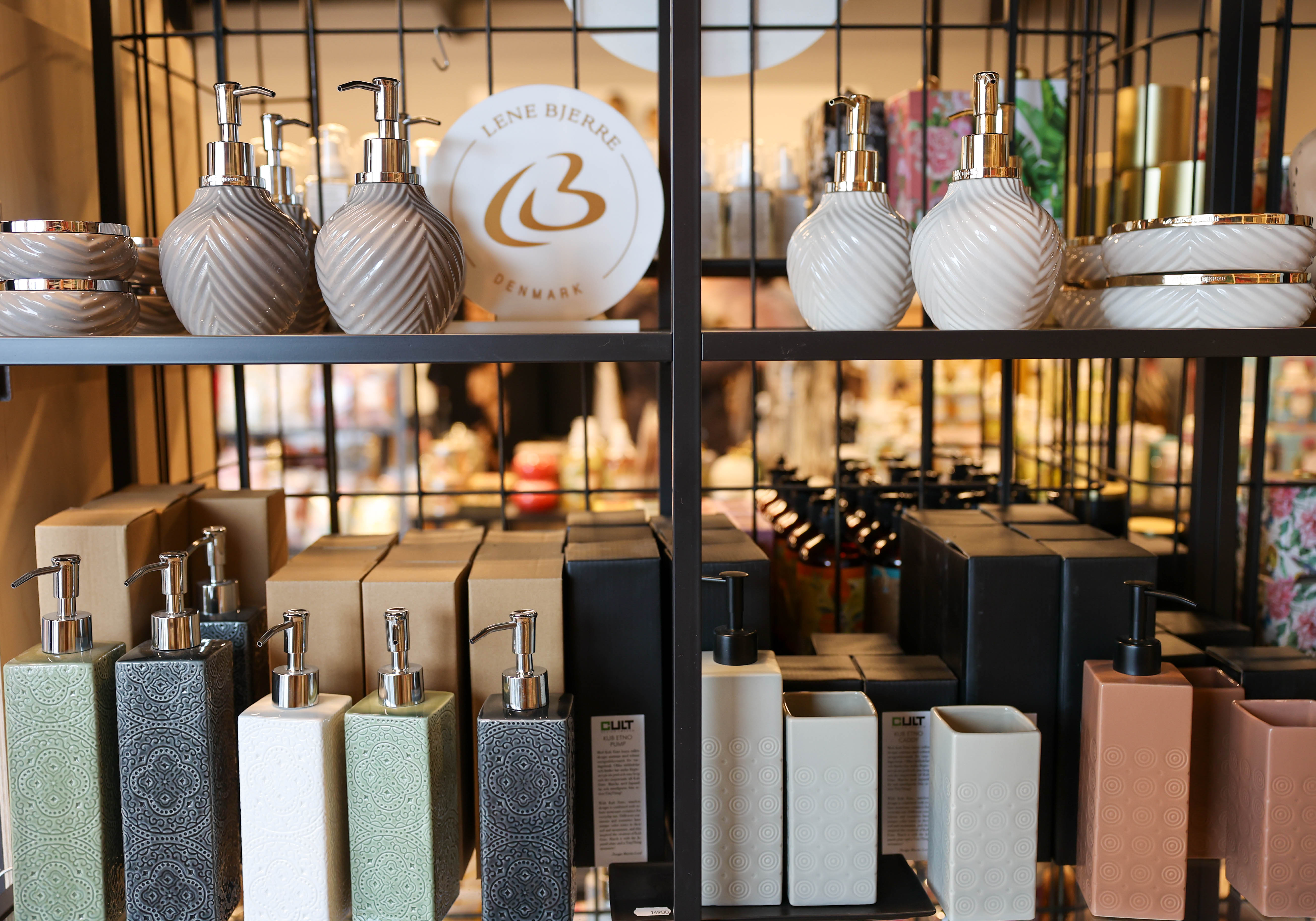 Butikshylla med tvålpumpar och badrumsaccessoarer i olika färger och mönster.