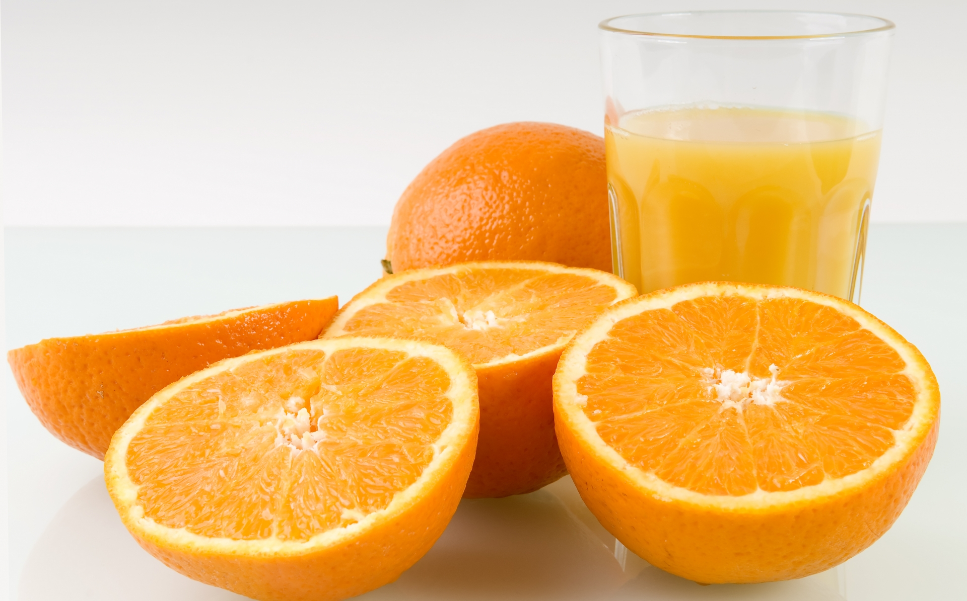 Gula apelsinhalvor med ett glas juice.