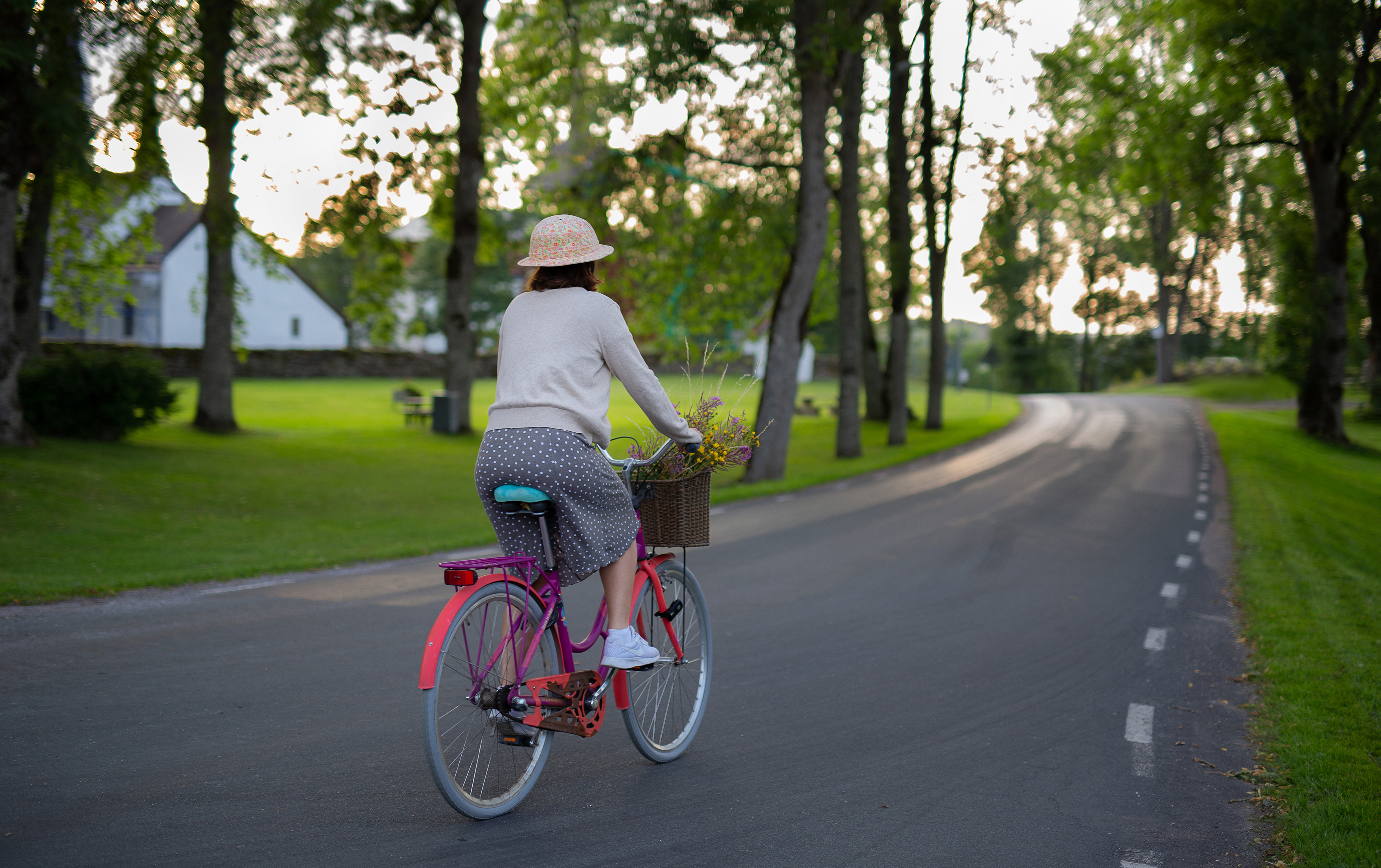 En kvinna på cykel på landsväg.