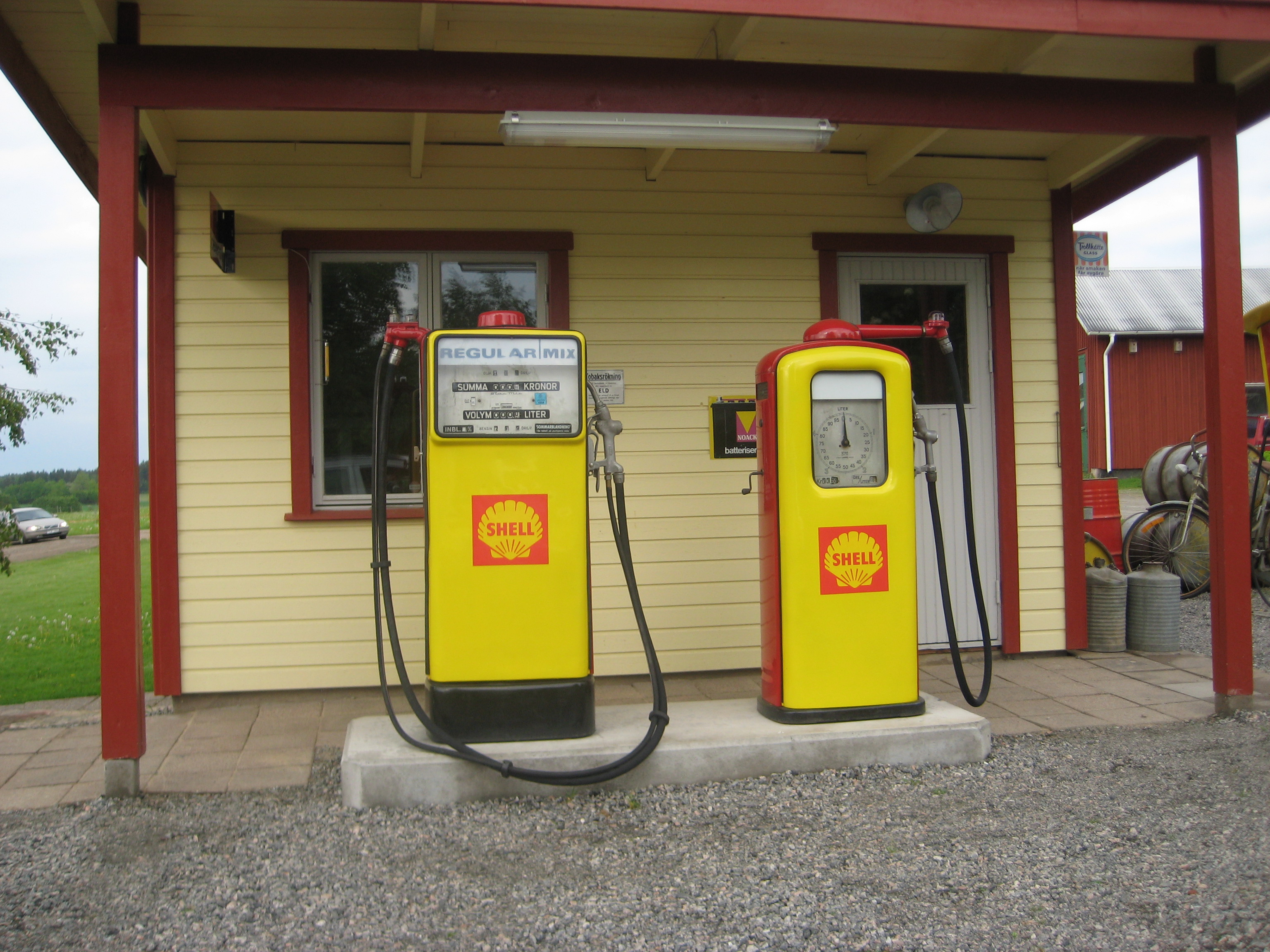 En gammal shellmack med två gula bensinpumpar framför.