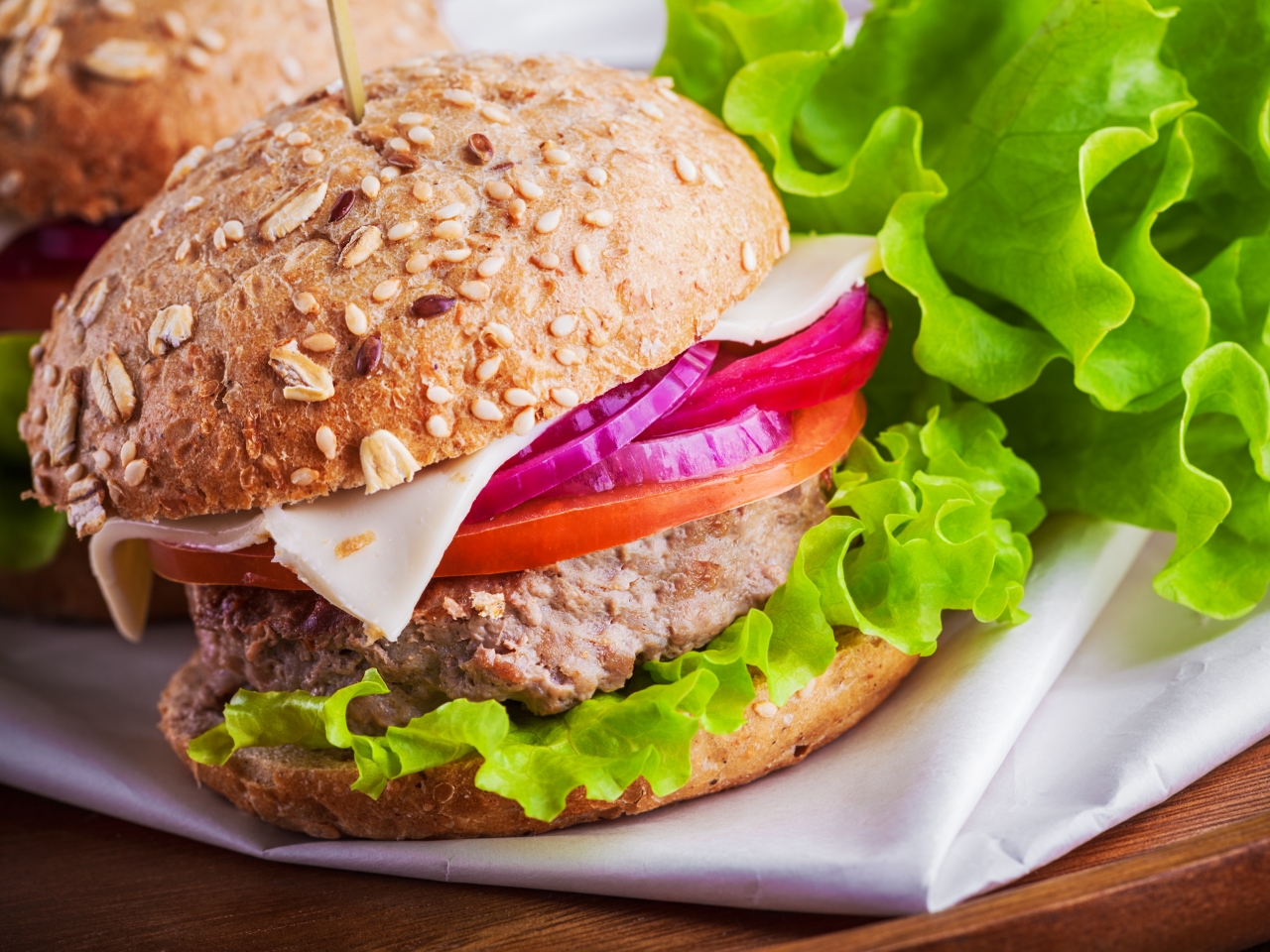 Hamburger in bread with salad, tomato, red onion and cheese.