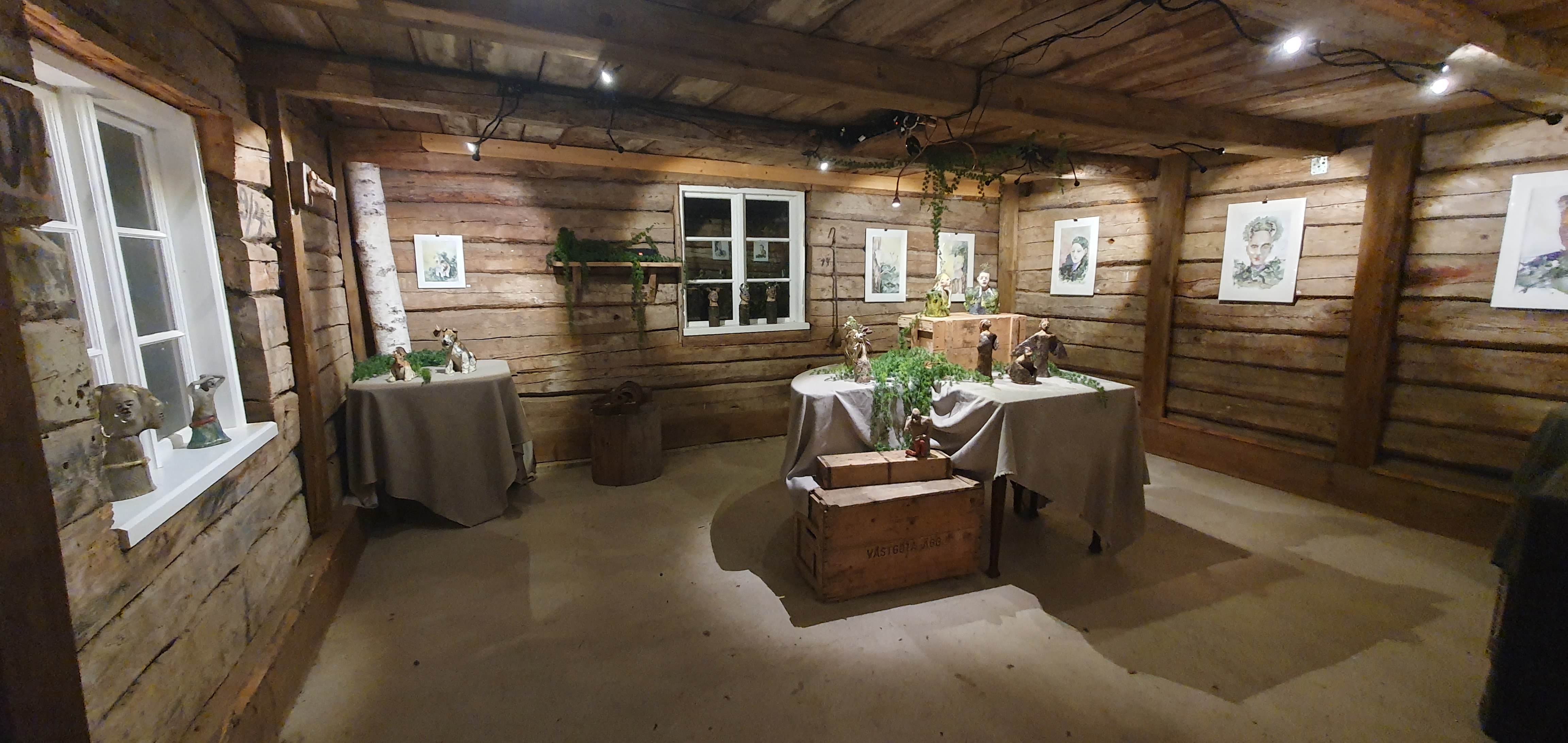 Utställning av tavlor i gammal byggnad med timmerväggar