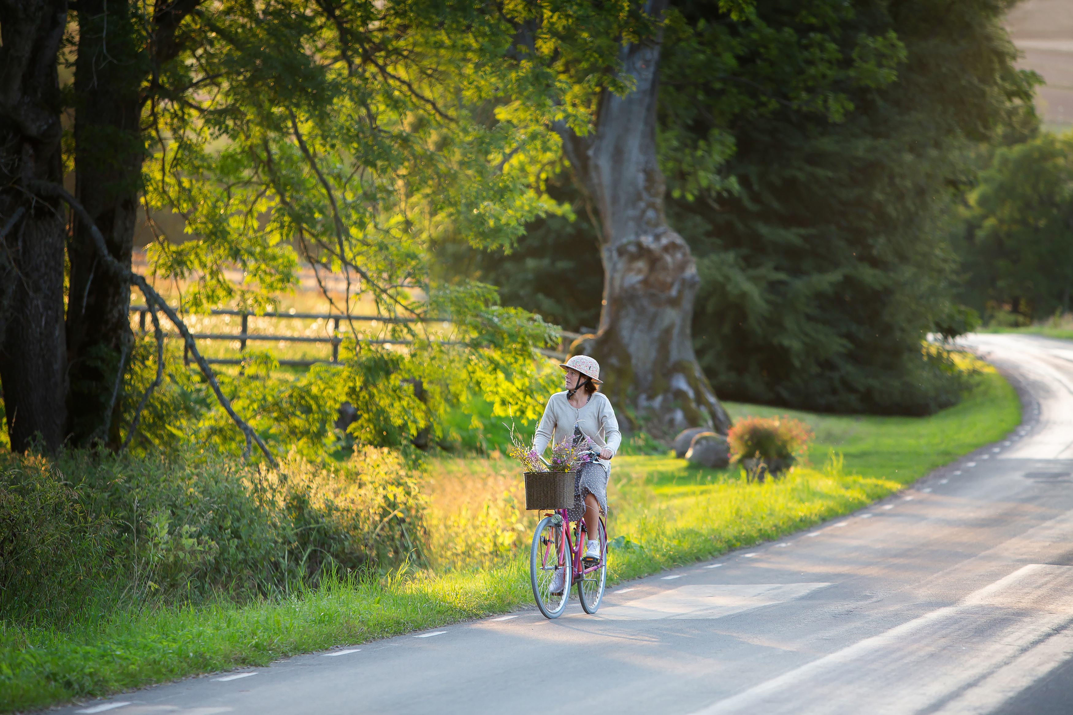 Kvinna cyklar förbi Kungslena i solen