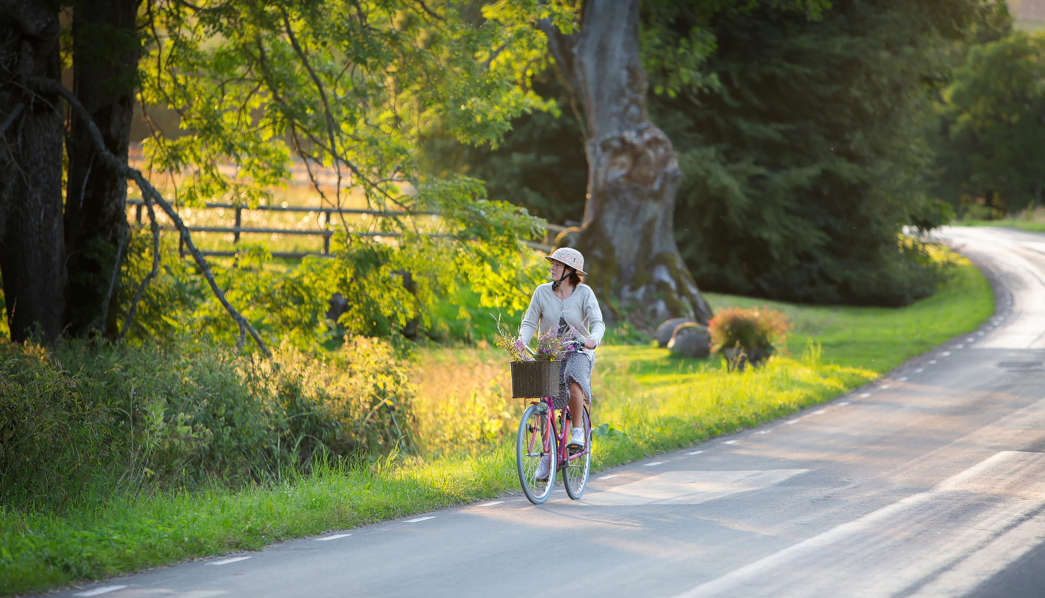 Kvinna cyklar förbi Kungslena i solen