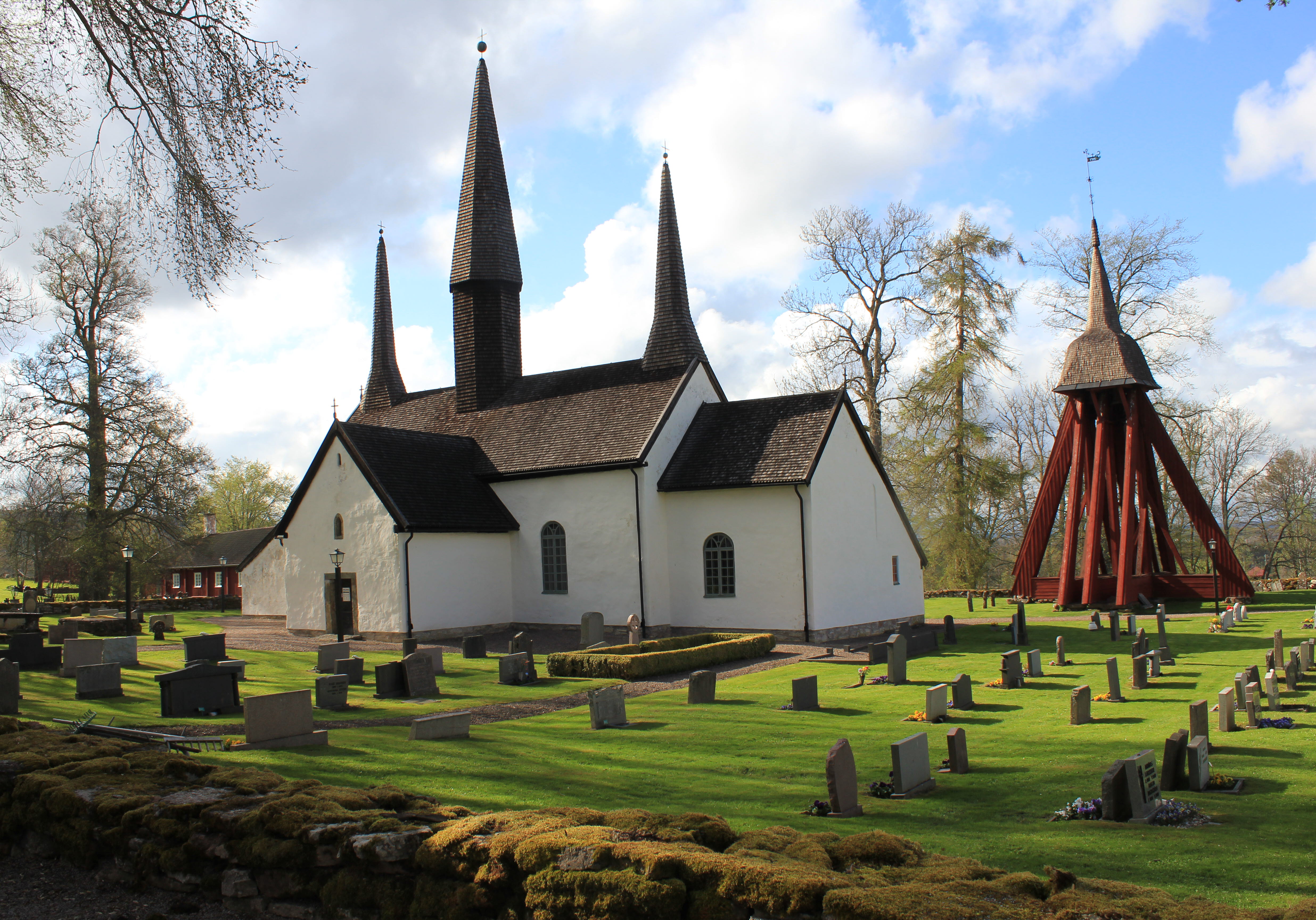 Kungslena kyrka. En vit stenkyrka med röd träklockstapel vid sidan.