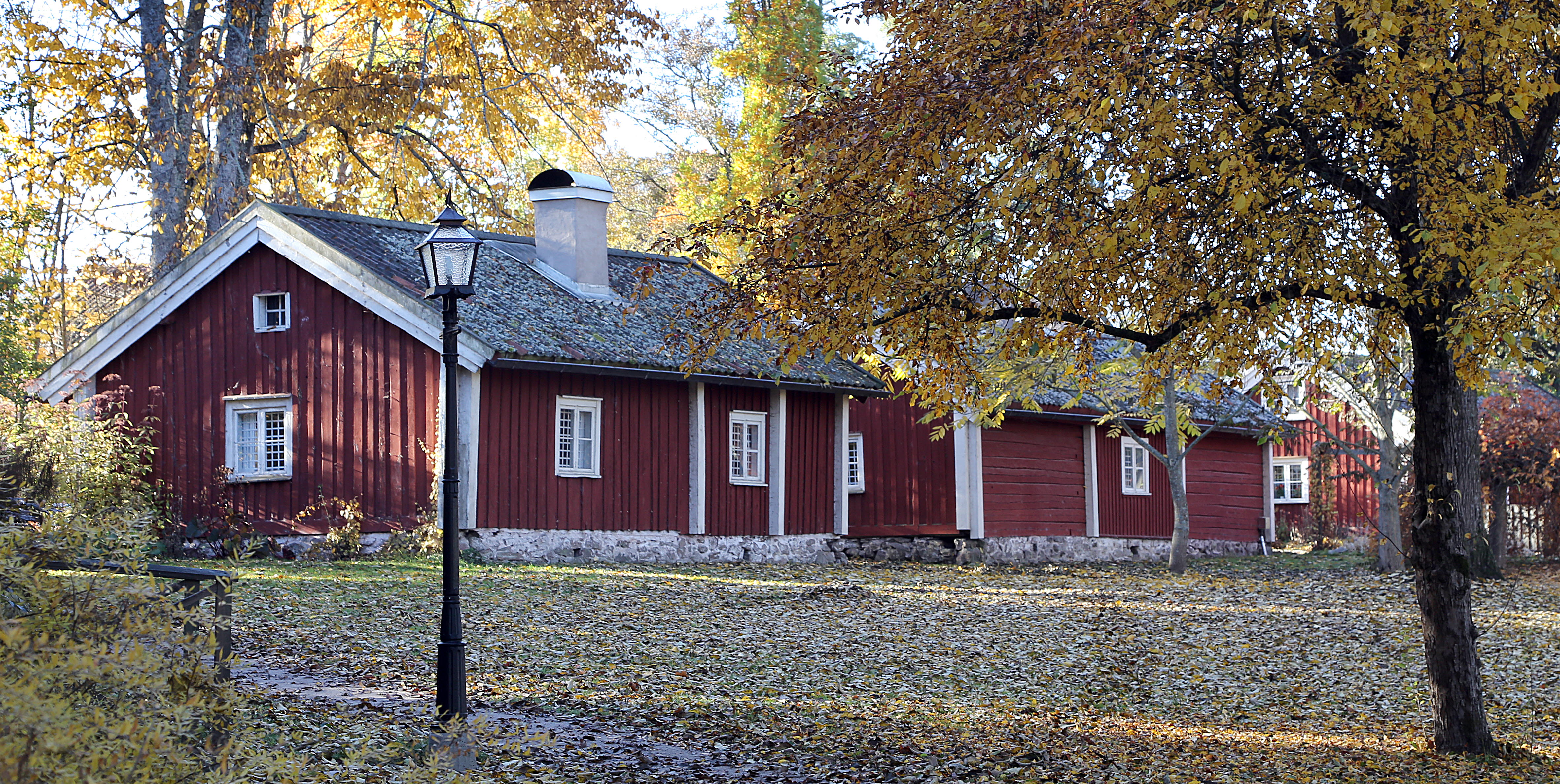 Två röda små trähus med vita knutar på Turbinhusön i Tidaholm i höstskrud.