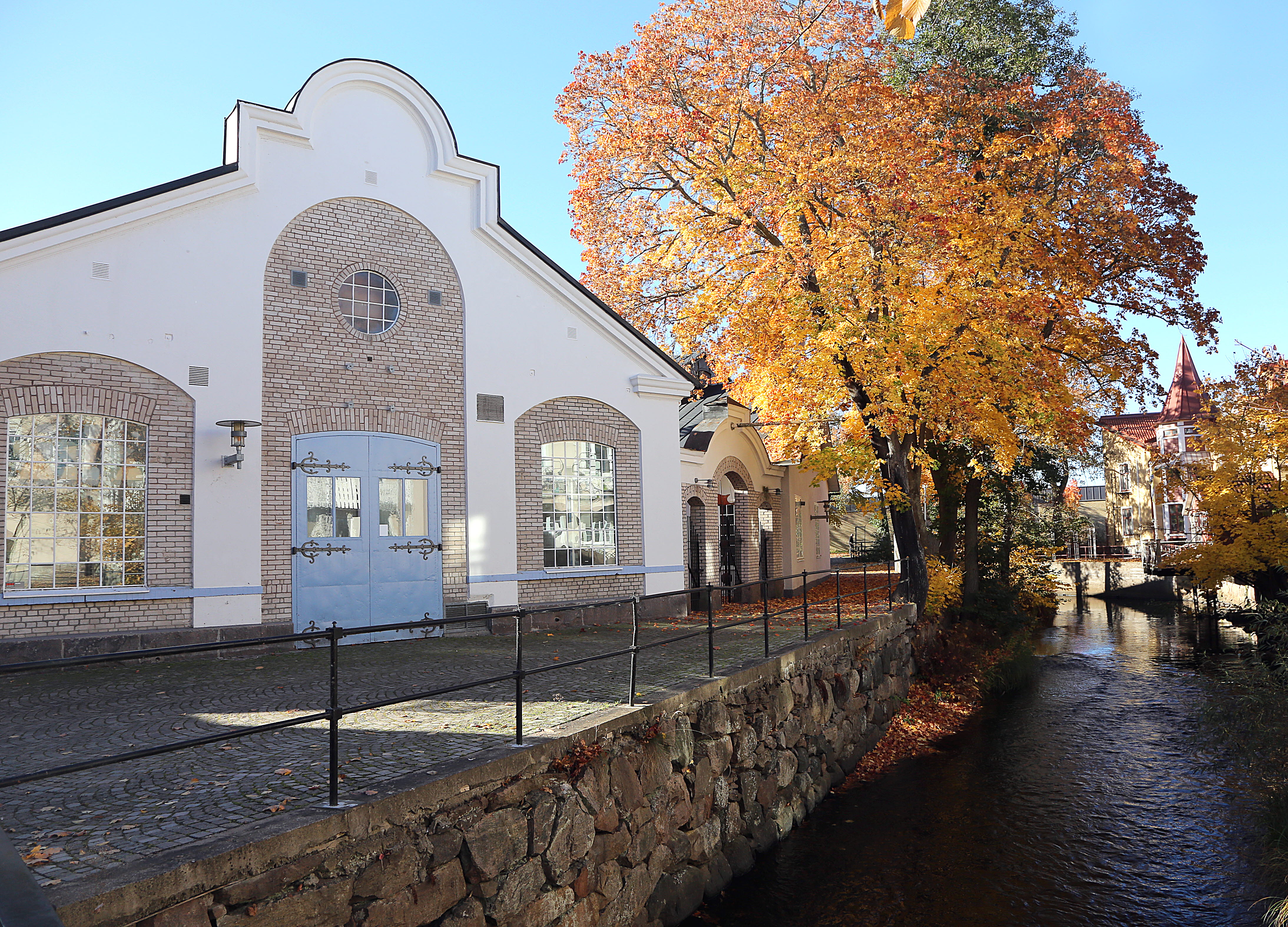 Vy över Tidaholms museum med ån Tidan framför i höstskrud.