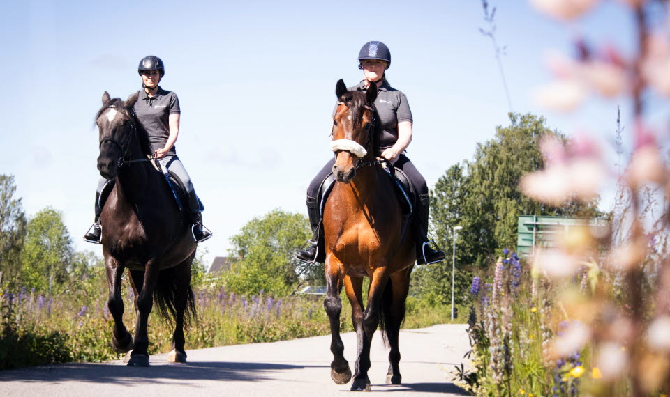 Två kvinnor rider utomhus.