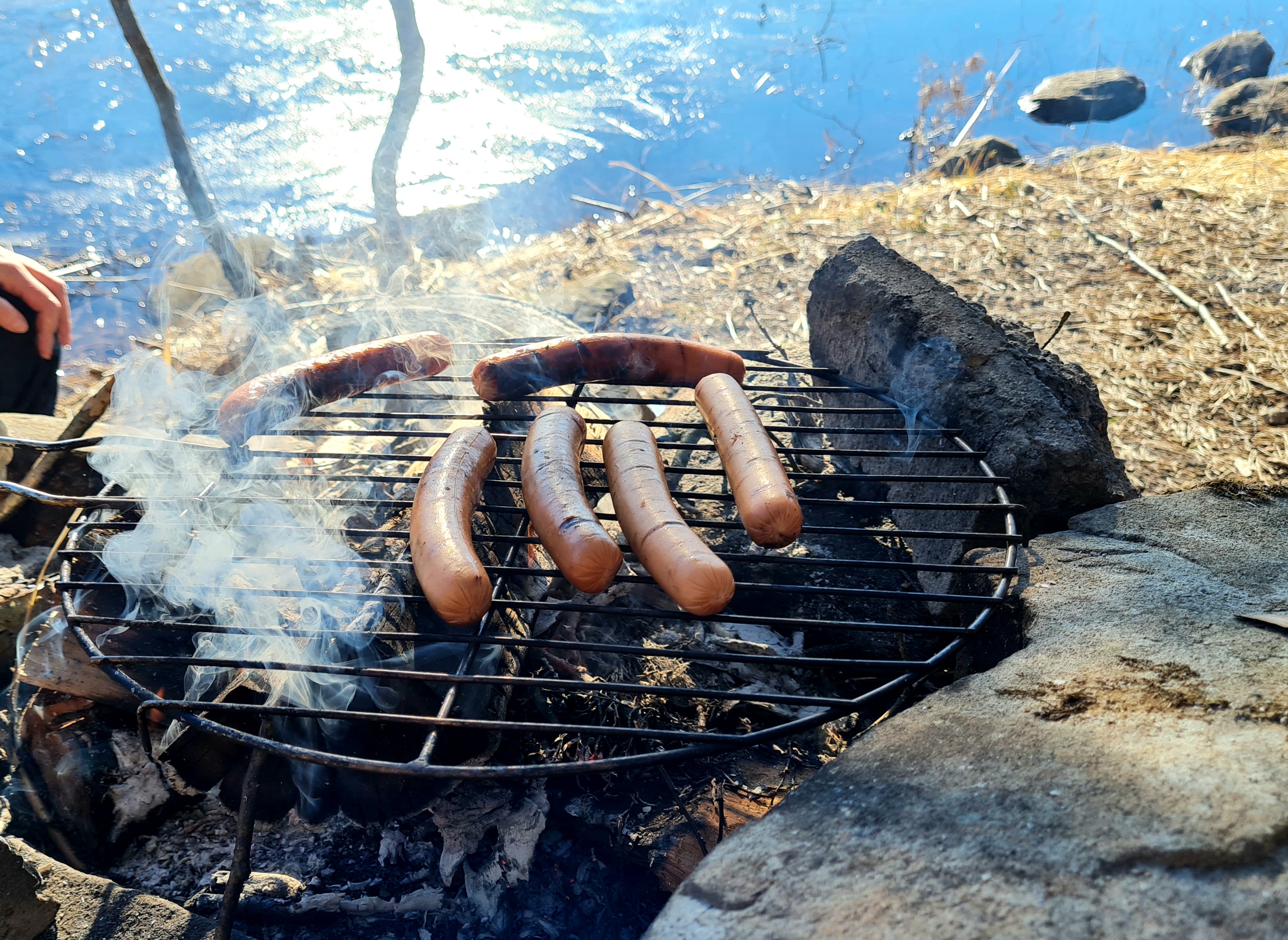 grillar korv utomhus i vårsolen