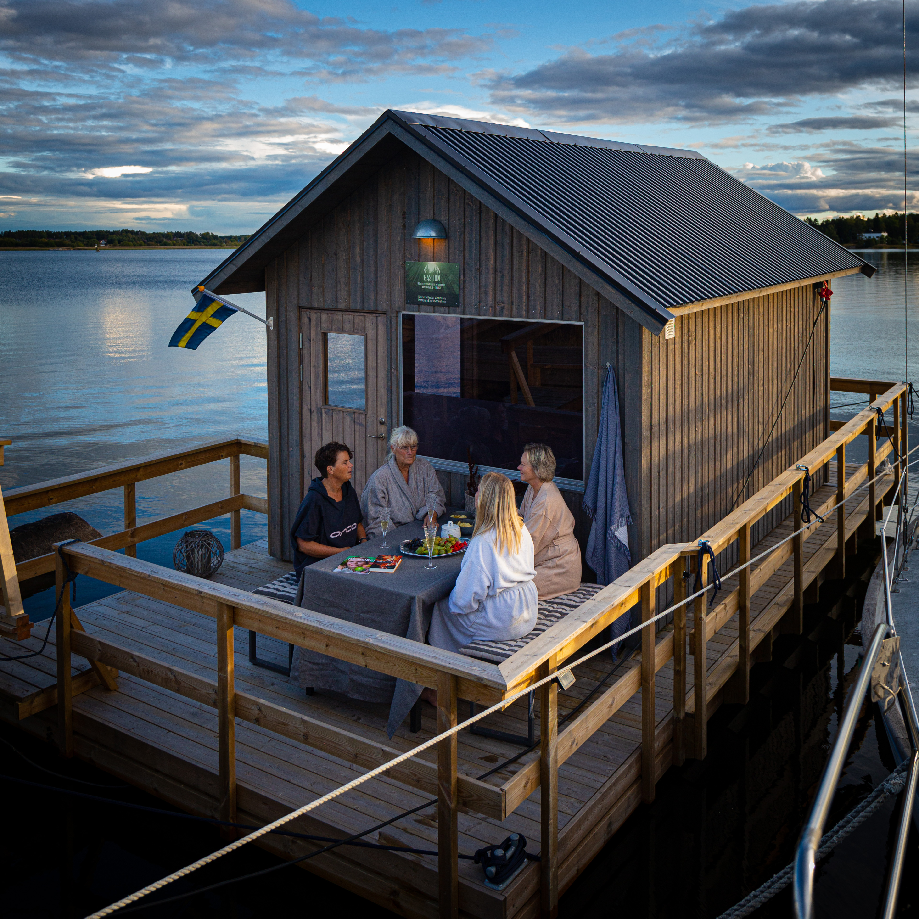 Four women at the deck in the sunsat at the Sauna raft