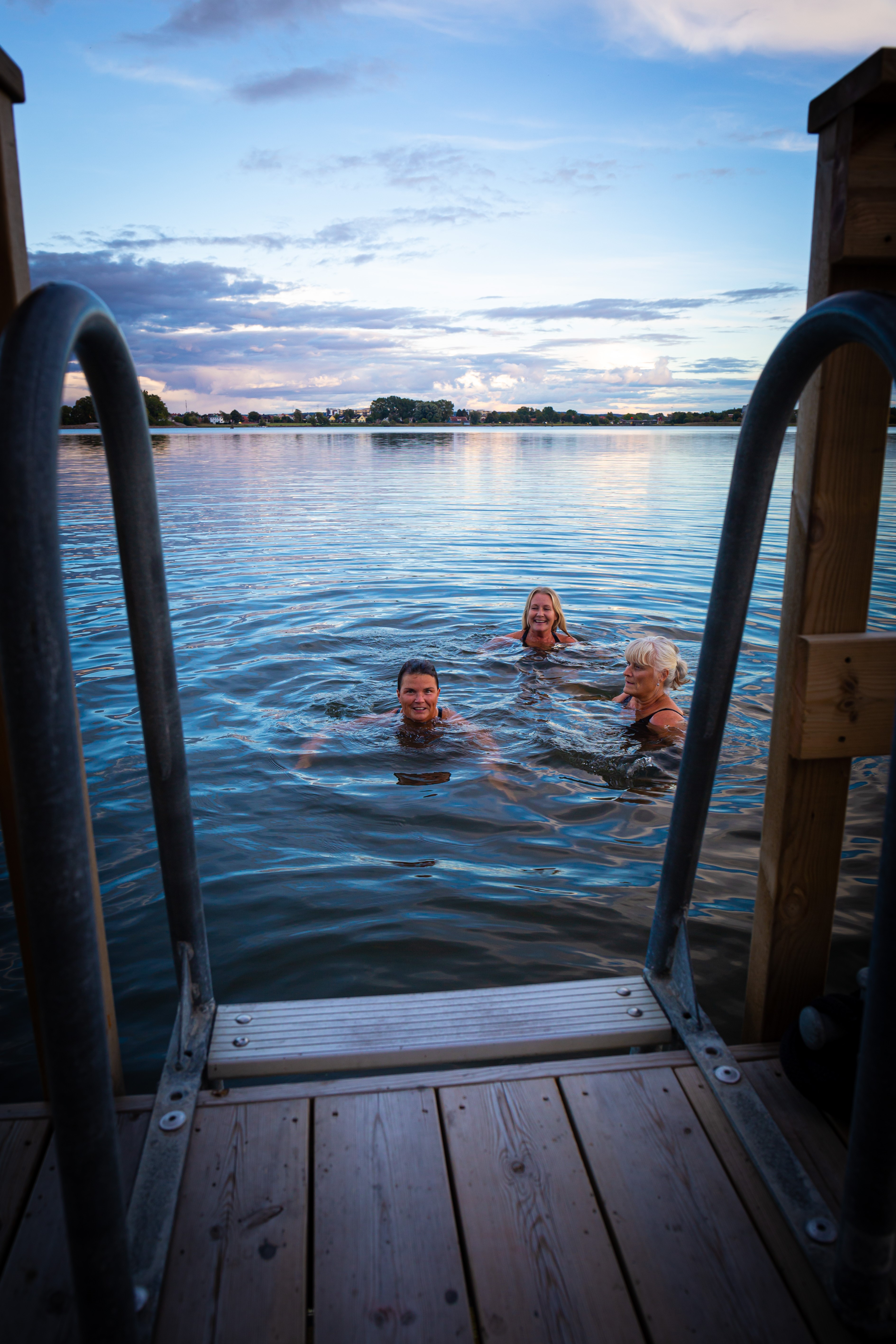 Three people are swimming in the sea from the sauna raft 