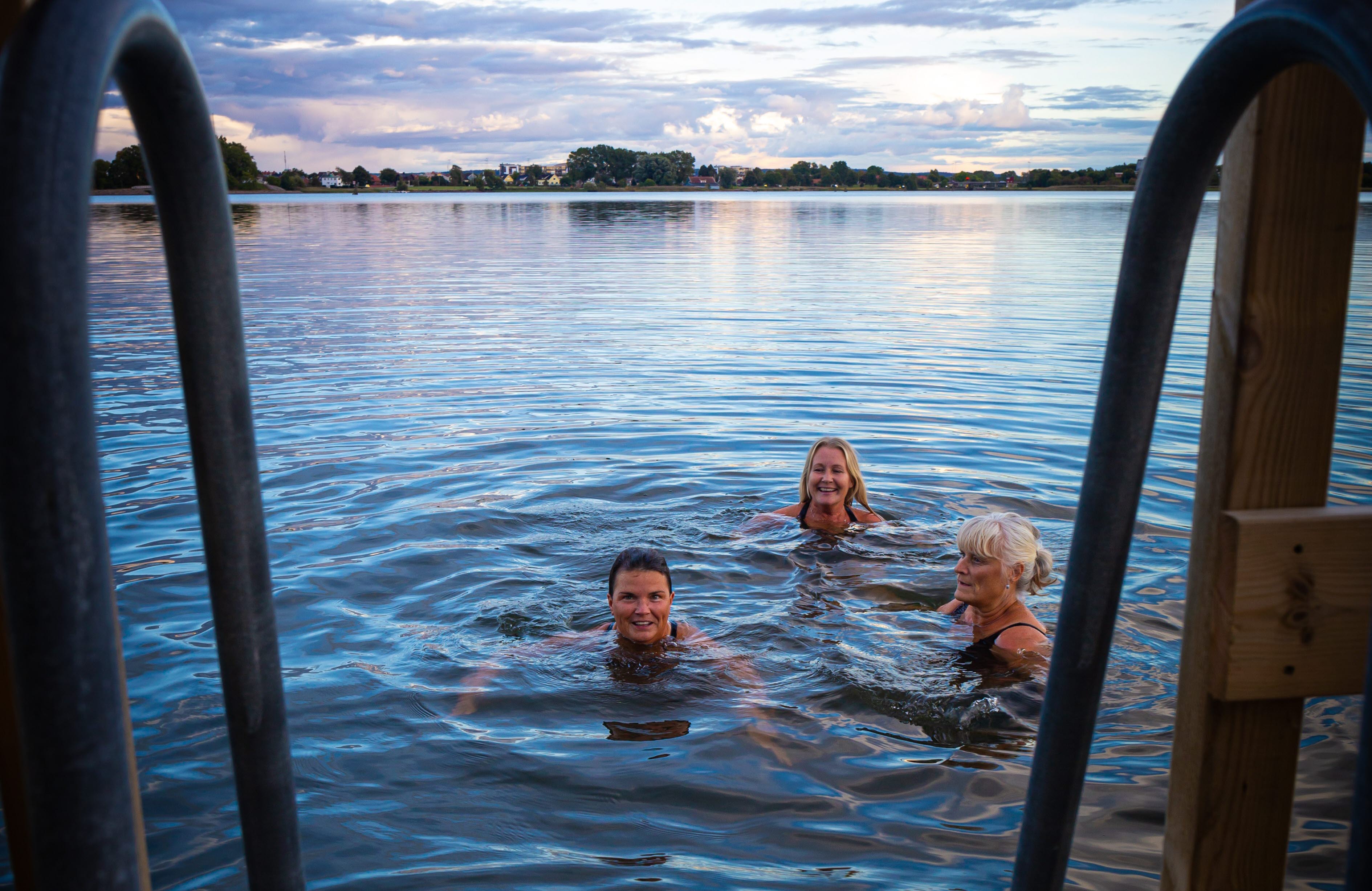 Tre personer badar i sjön från Bastuflotten 