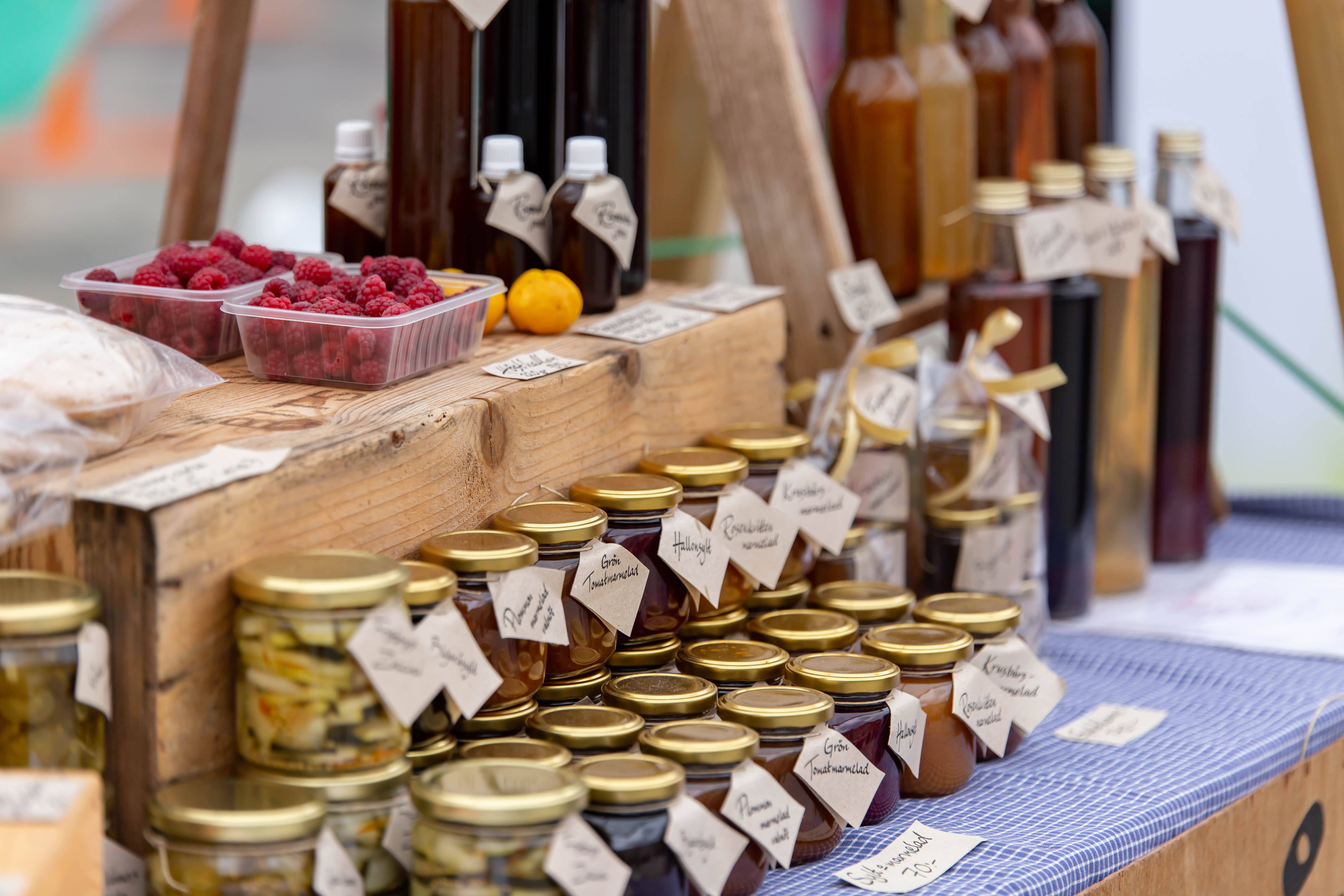 Varierade lokalproducerade produkter på ett marknadsstånd så som marmelad och bär.