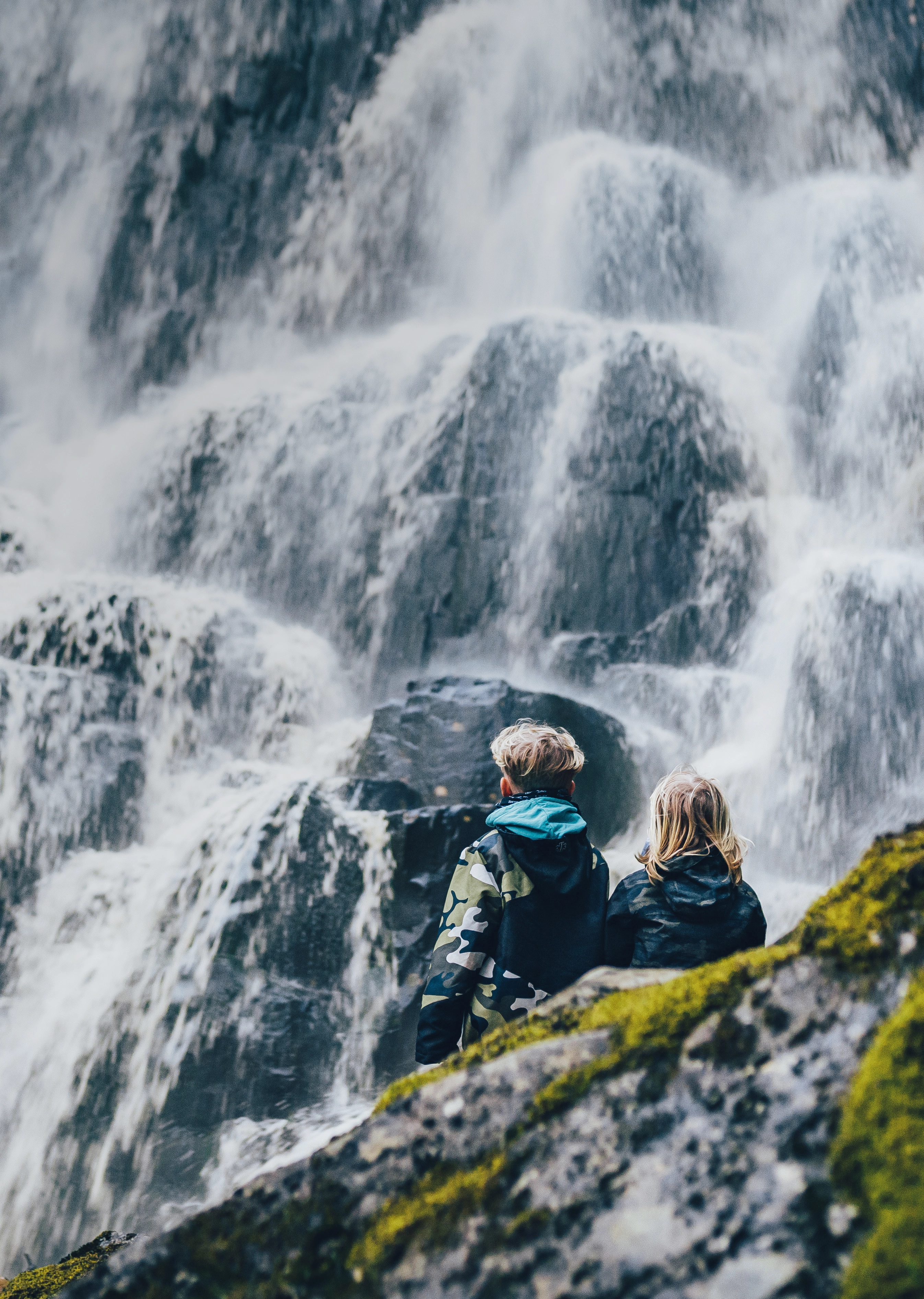 Två barn som sitter och tittar på ett vattenfall