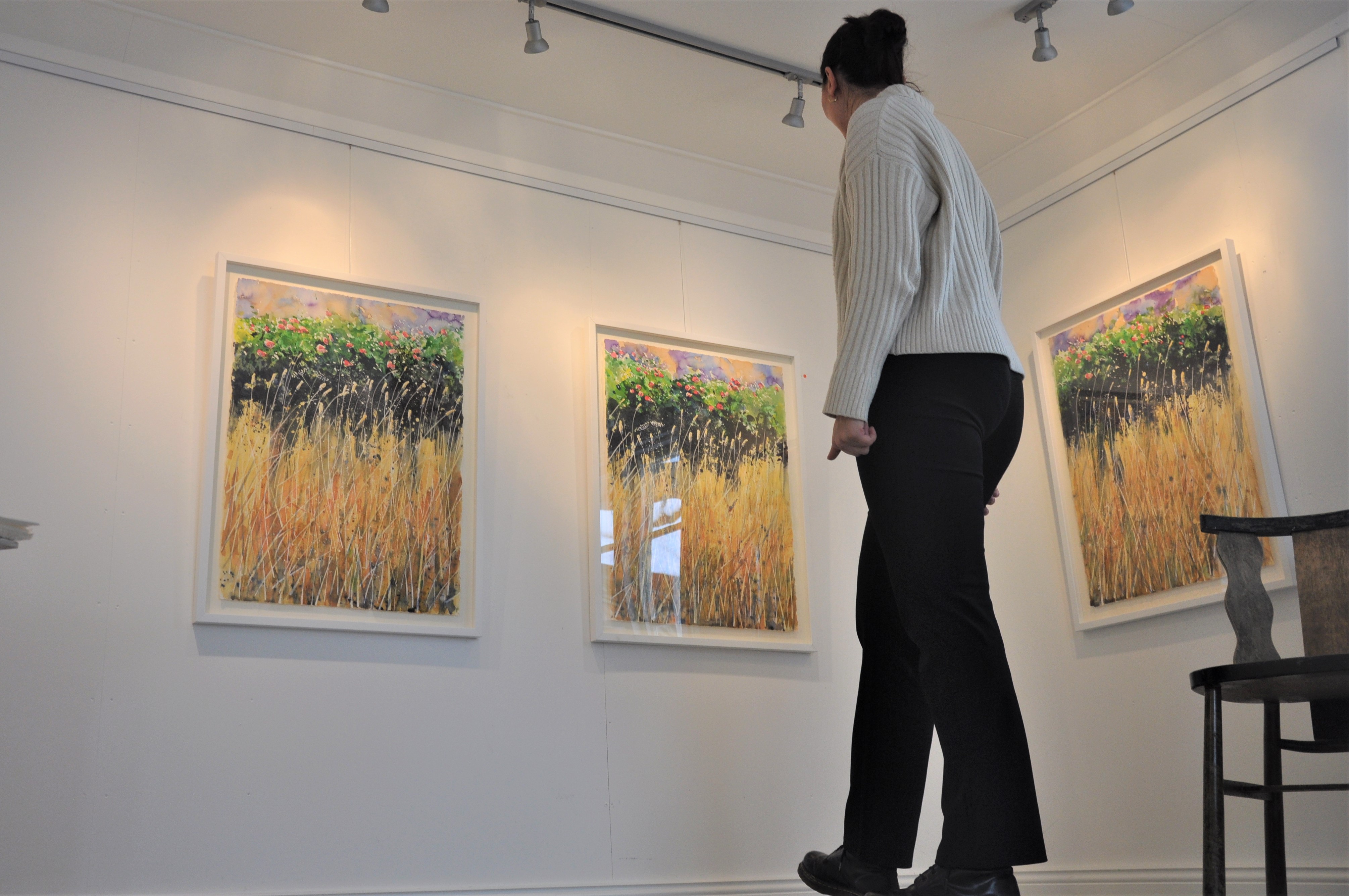 kvinna ser på tavlor i galleri