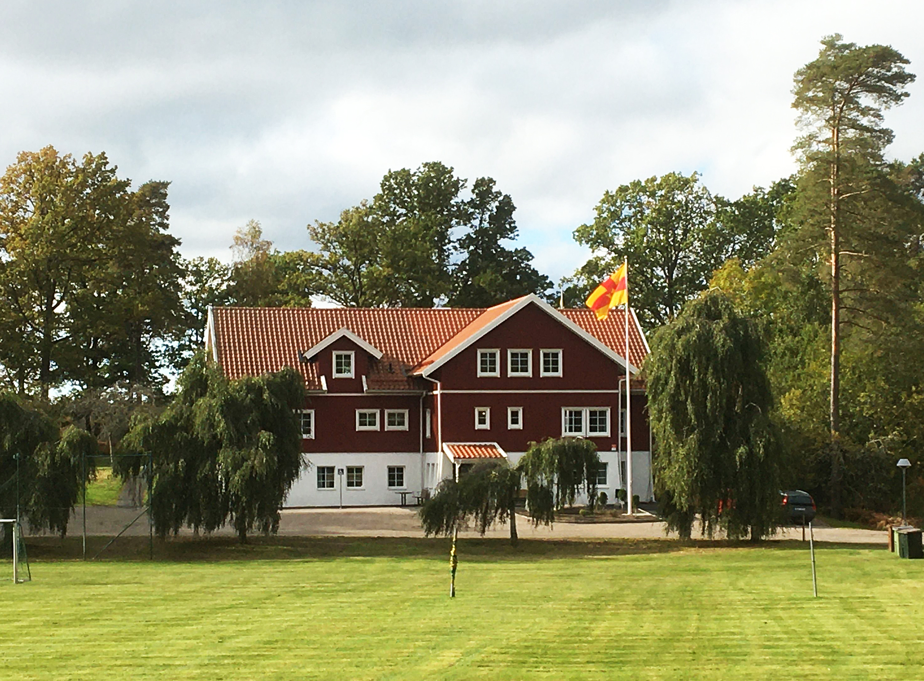 Röd villa med en stor gräsmatta framför 