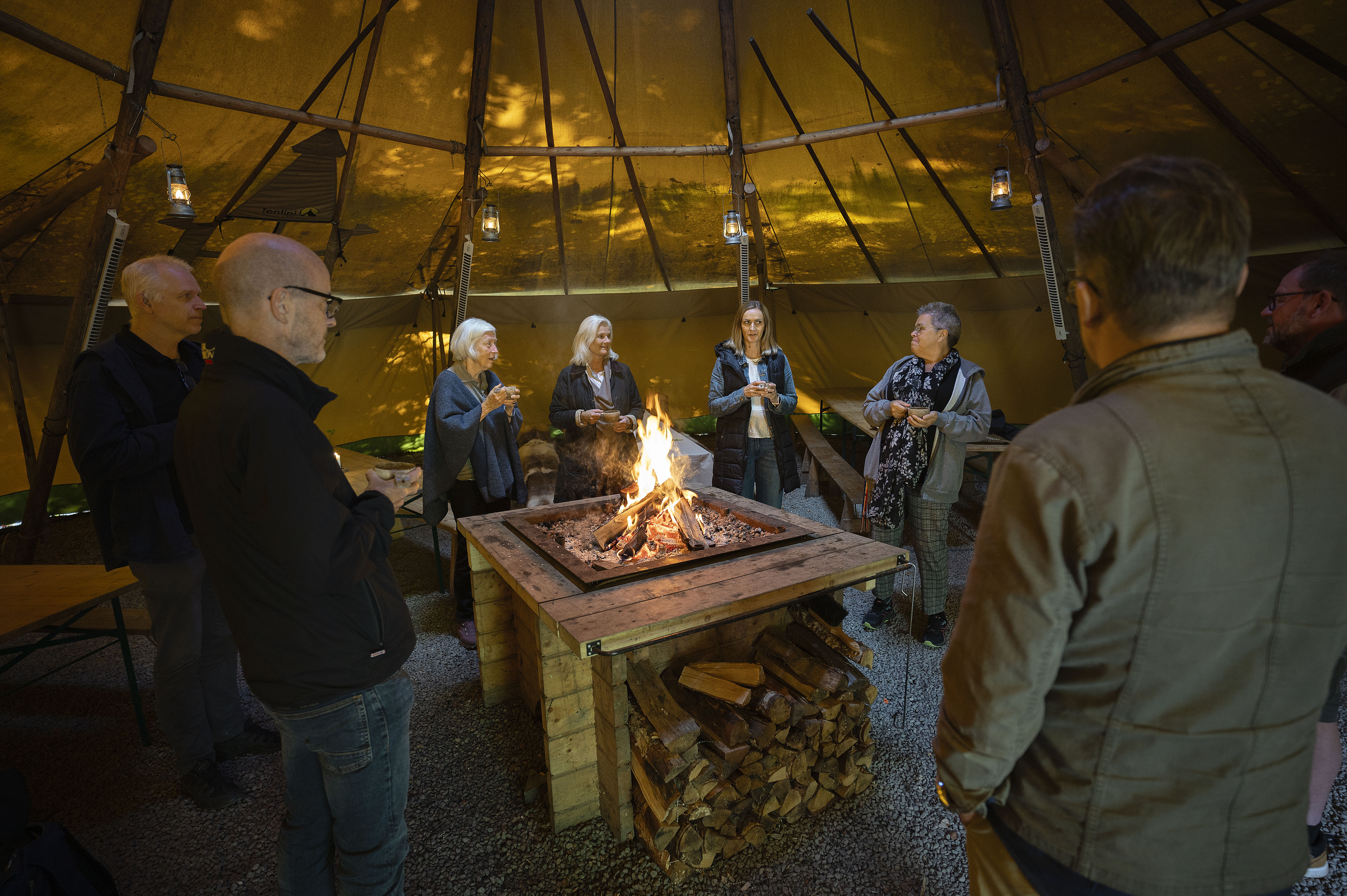 Konferens på Hunneberg, människor samlade runt brasa i tält. 