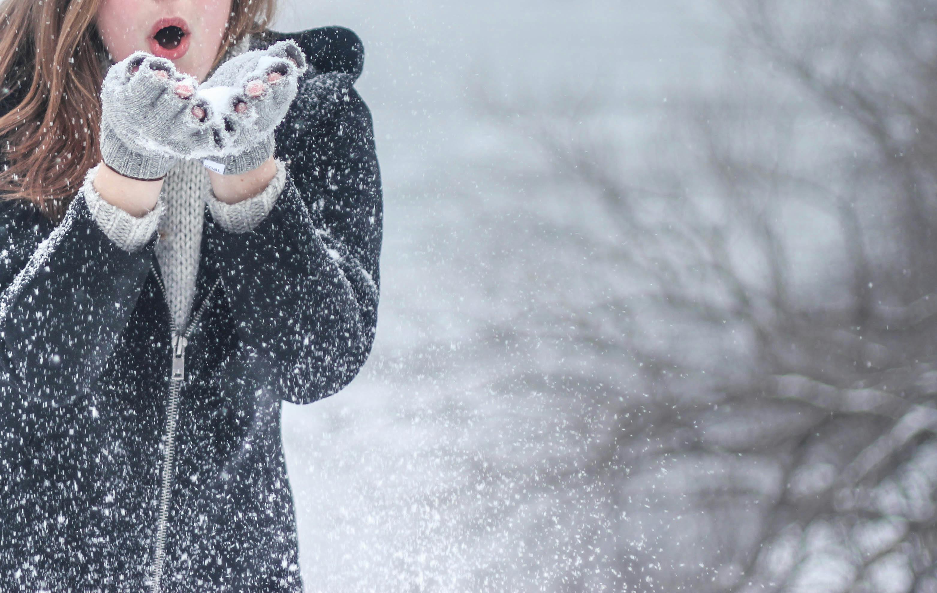 Person blowing snow out of her hands