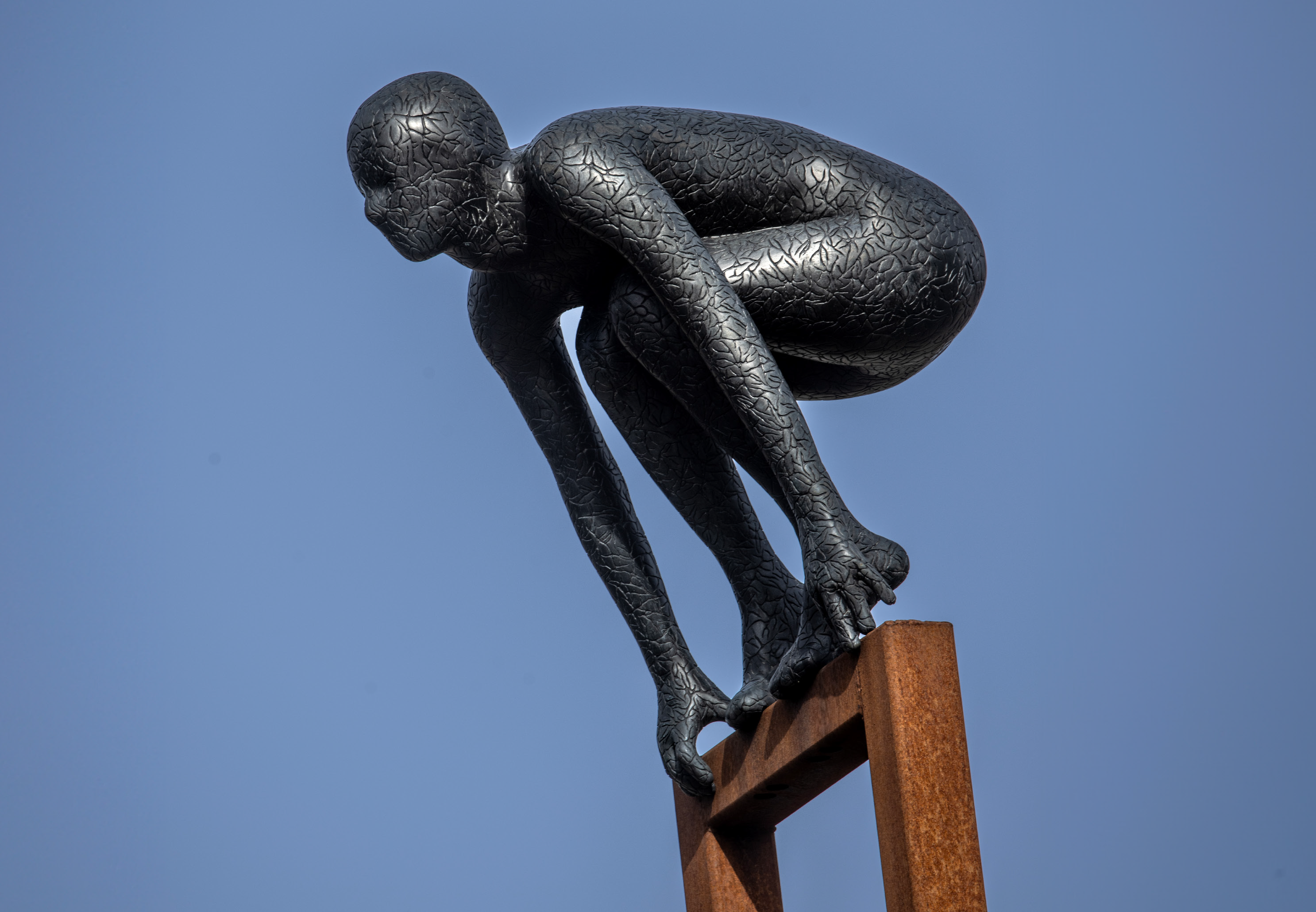 Skulptur av en man som böjer sig ner