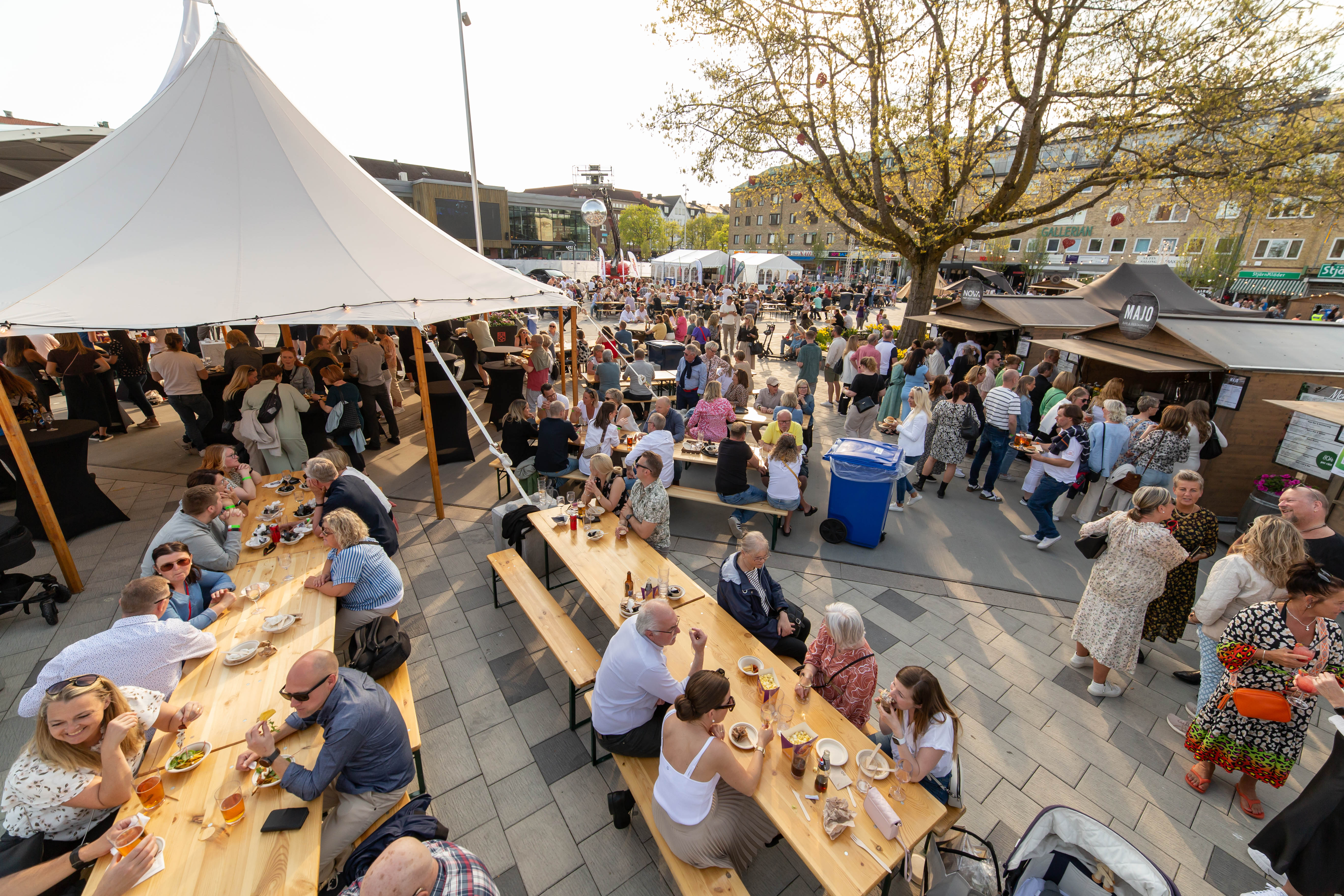 Vy över torget där människor sitter vid långbord och äter mat
