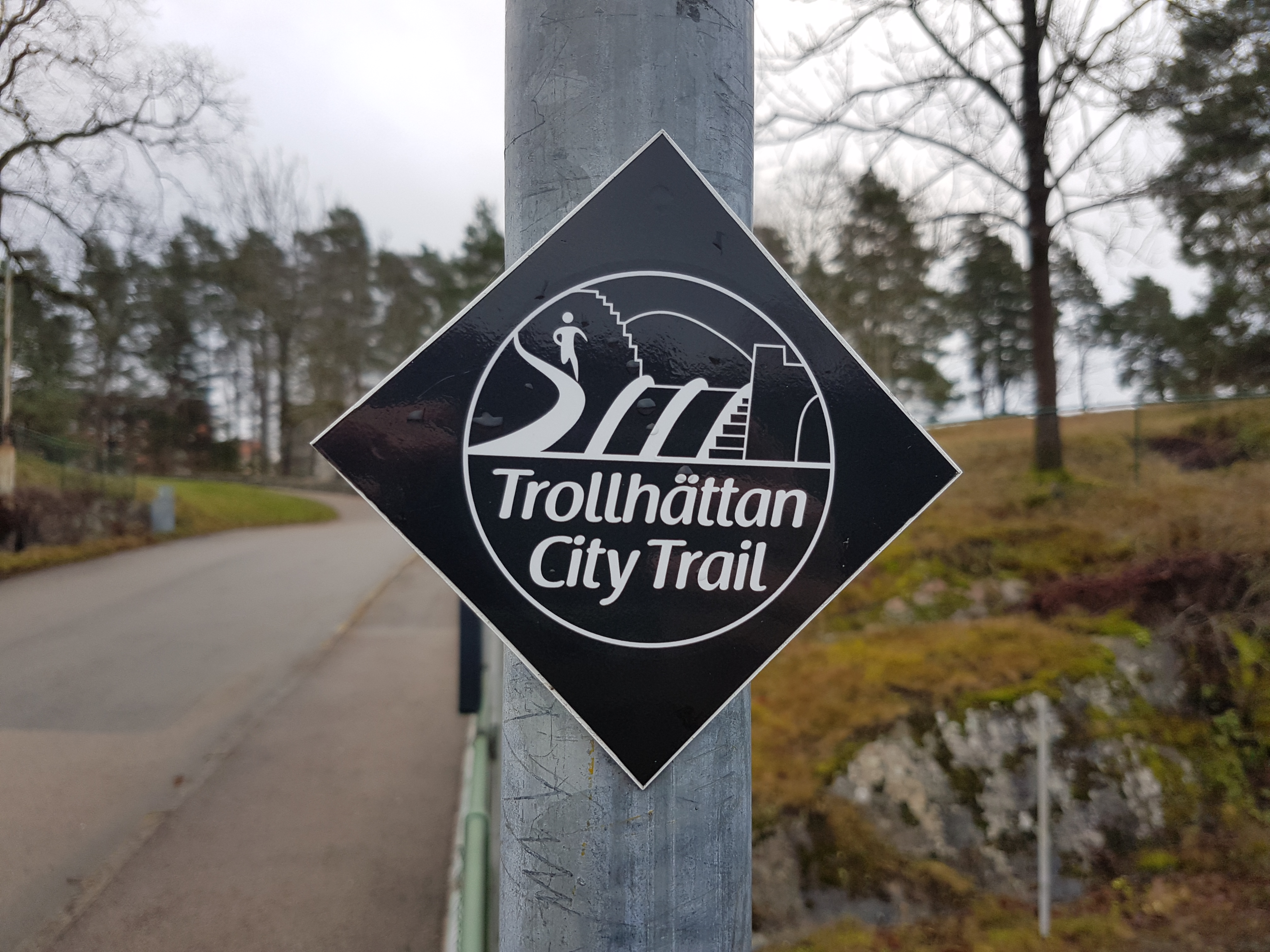 Svartvit skylt för Trollhättan City Trail.