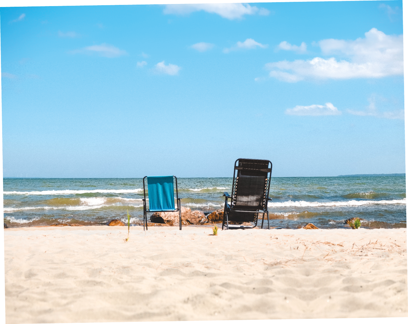 Två solstolar på en sandstrand