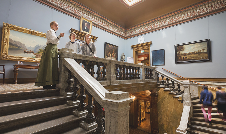Museum guide showing two guests around inside Vänersborg museum.