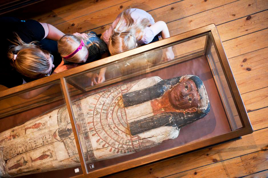 Barn som tittar på den egyptiska sarkofagerna i Vänersborgs museum,