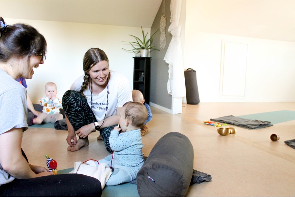 yogalärare ler mot ett barn på familjeyoga